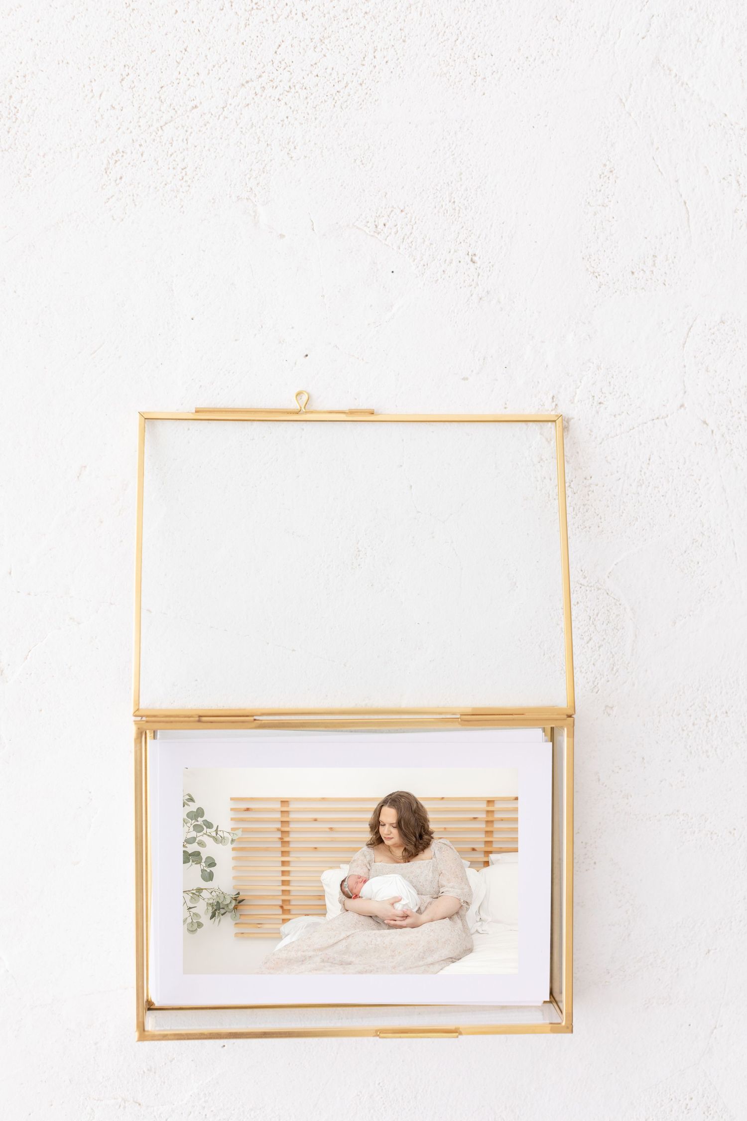 Glass photo display box with gold edging displaying beautiful newborn photos by Columbus, GA newborn photographer.