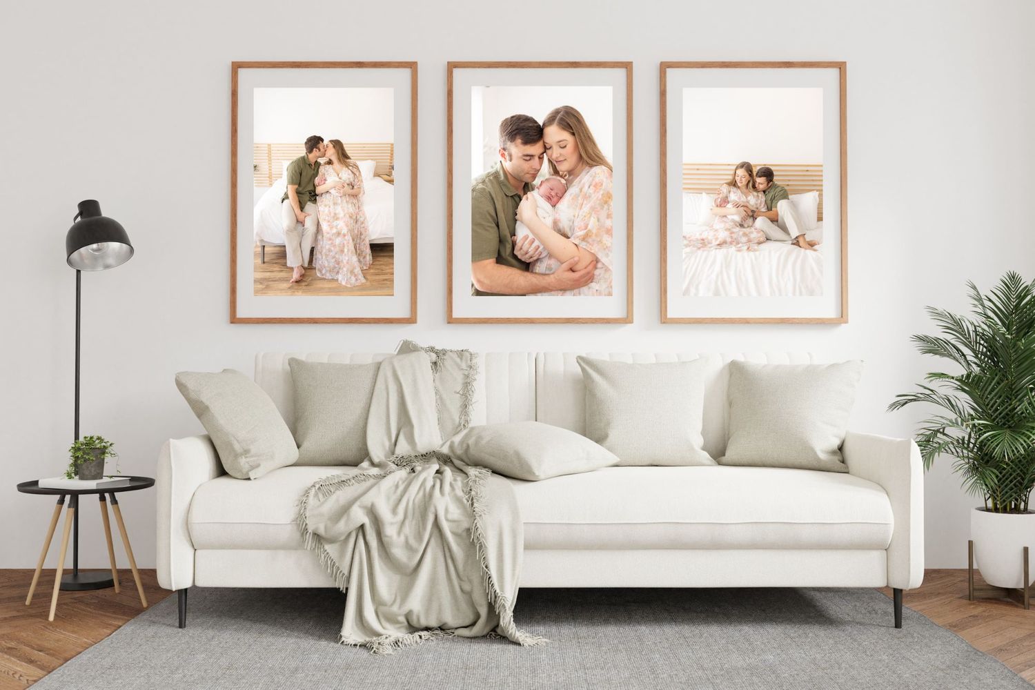 Three framed family portraits displayed above modern white couch with throw blanket in contemporary living room.