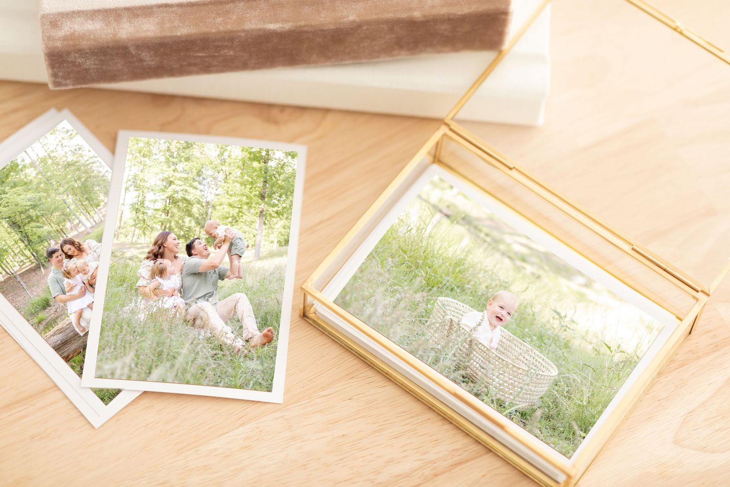 Printed family photos displayed on a wooden table with a gold glass box and white tissue paper.