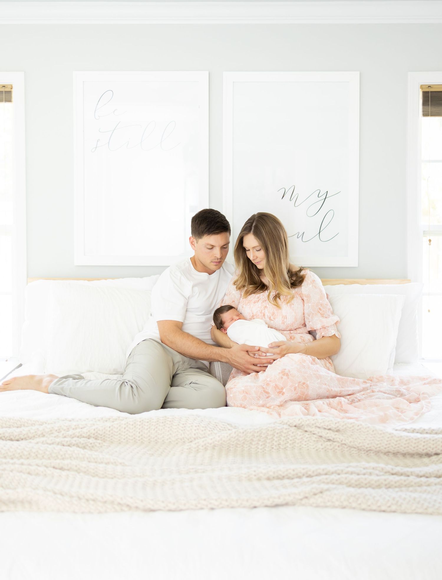 New parents relaxing on the bed holding their newborn during their lifestyle newborn portrait session by Columbus, GA newborn photographer.