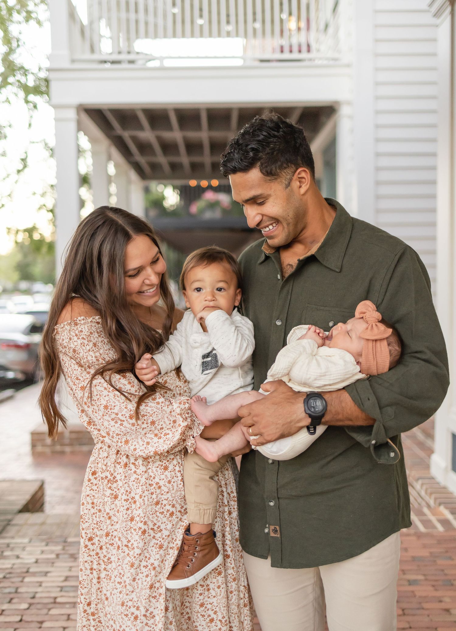 A mom and dad smile at their two kids in their arms during their Columbus, GA family photos.