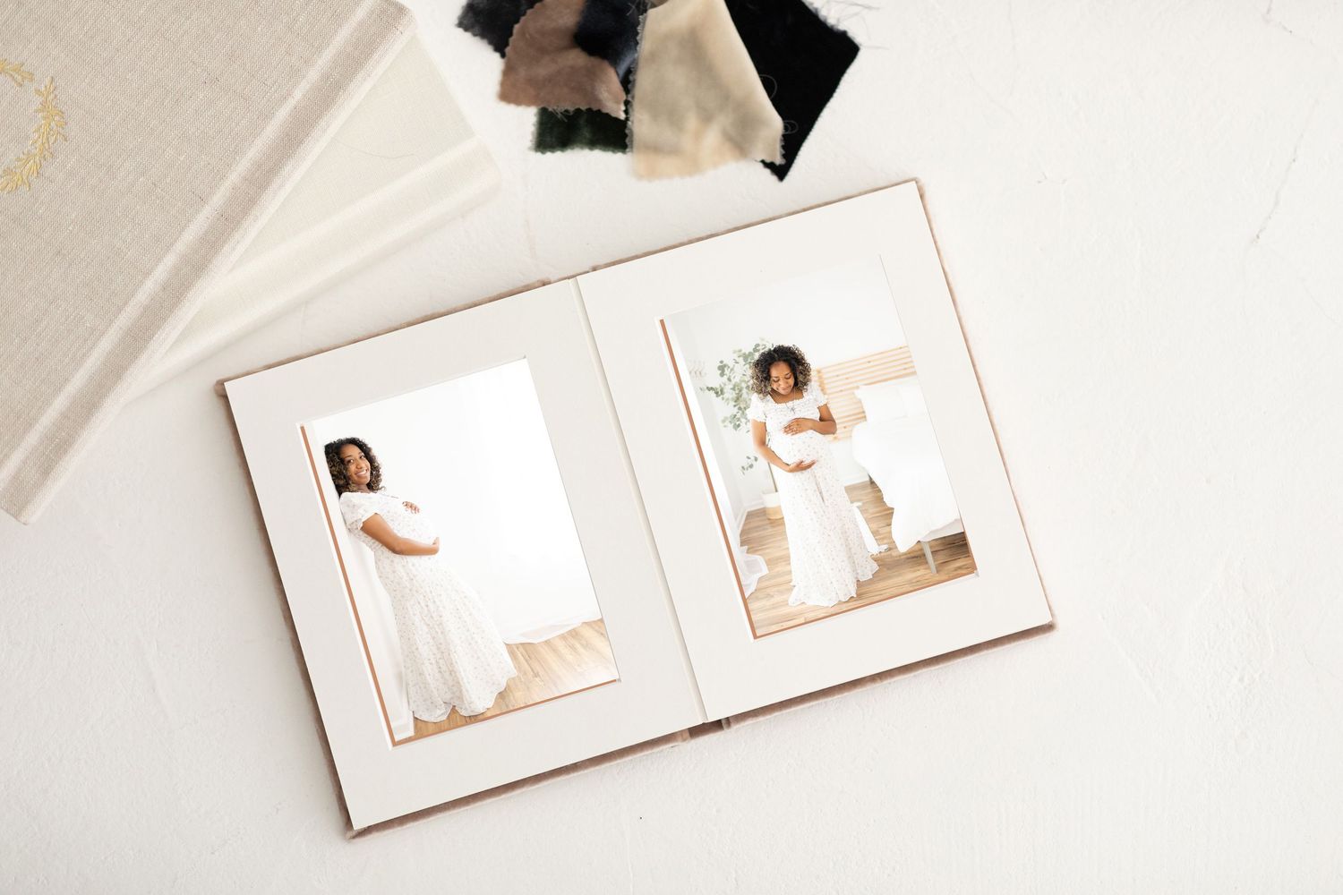 A white photo album lies open on a light surface showing artistic portraits in soft, muted tones.