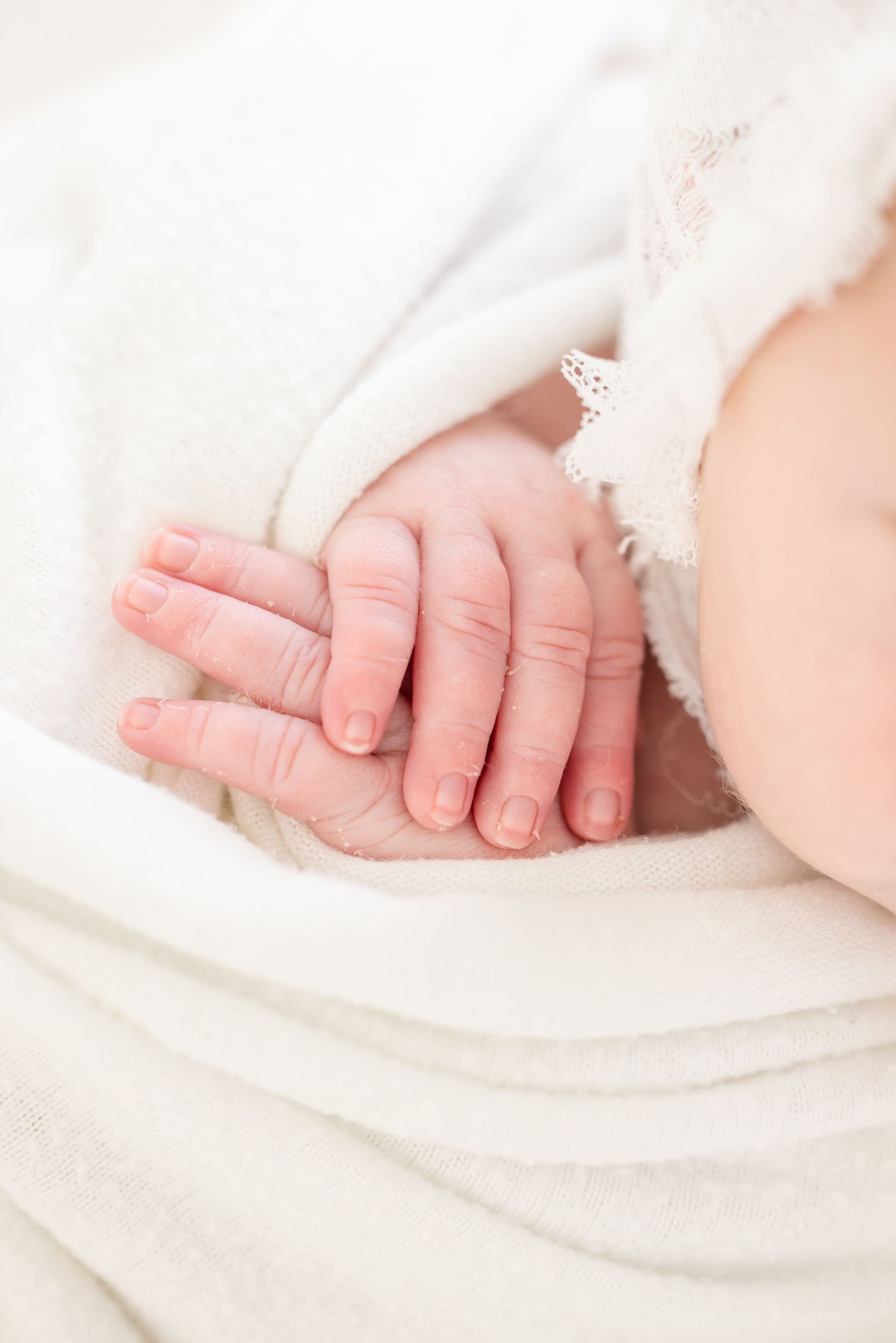 Close up of tiny newborn hands resting on a white blanket by Columbus GA newborn photographer.