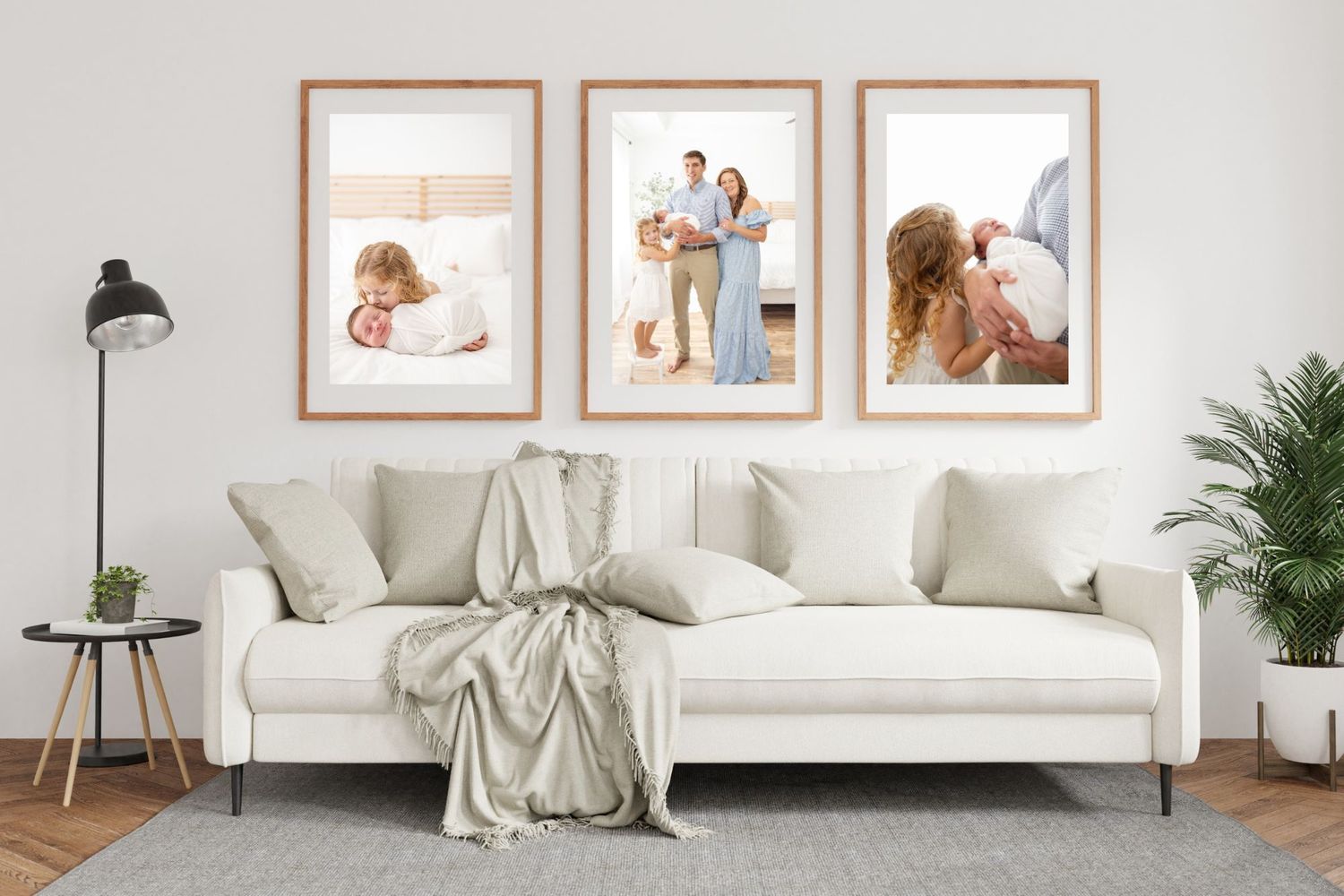 Three framed newborn and family portrait photos displayed above a white sofa in a bright modern living room.