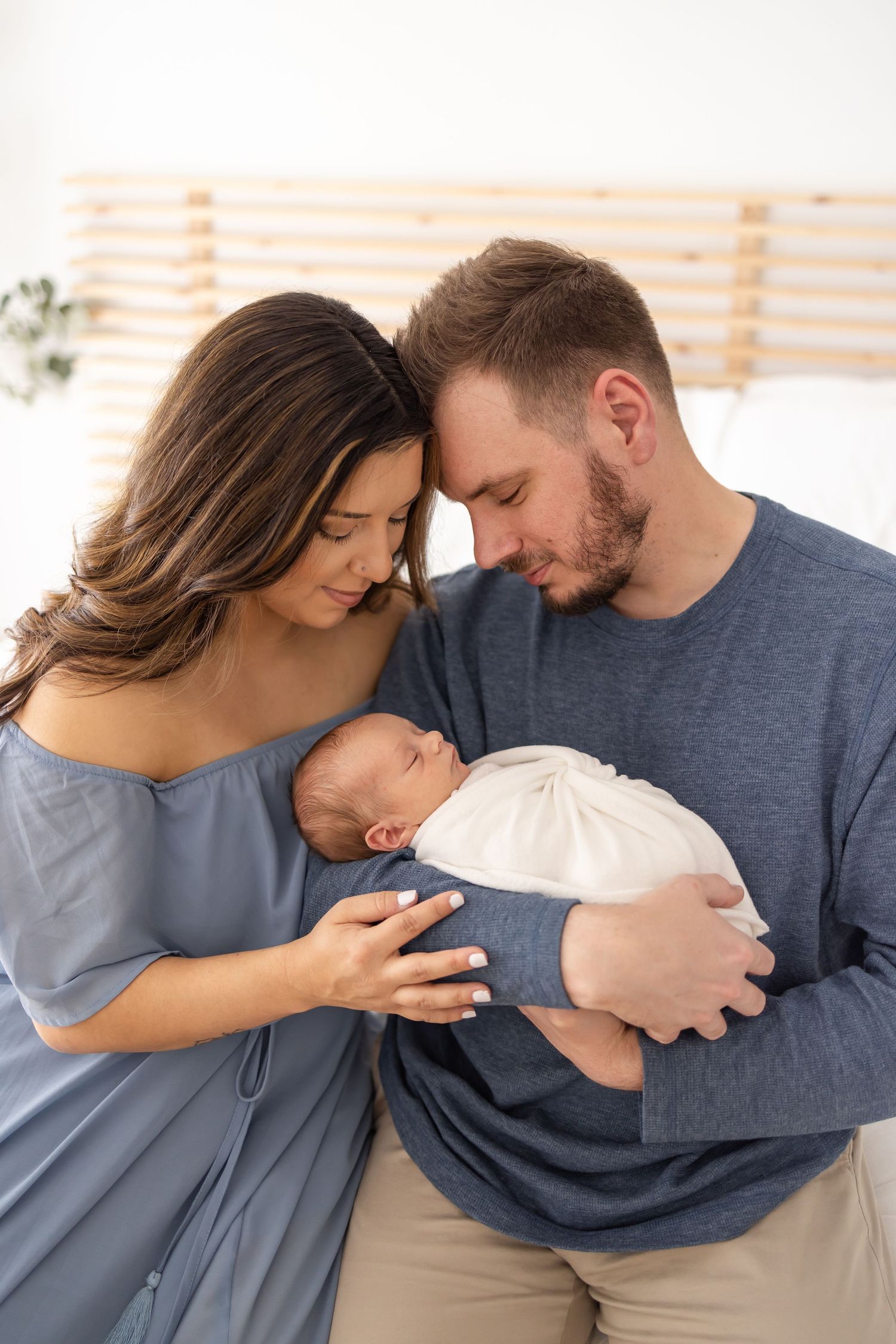 New parents dressed in blue share a tender moment with their newborn at their Columbus, GA newborn photography session.