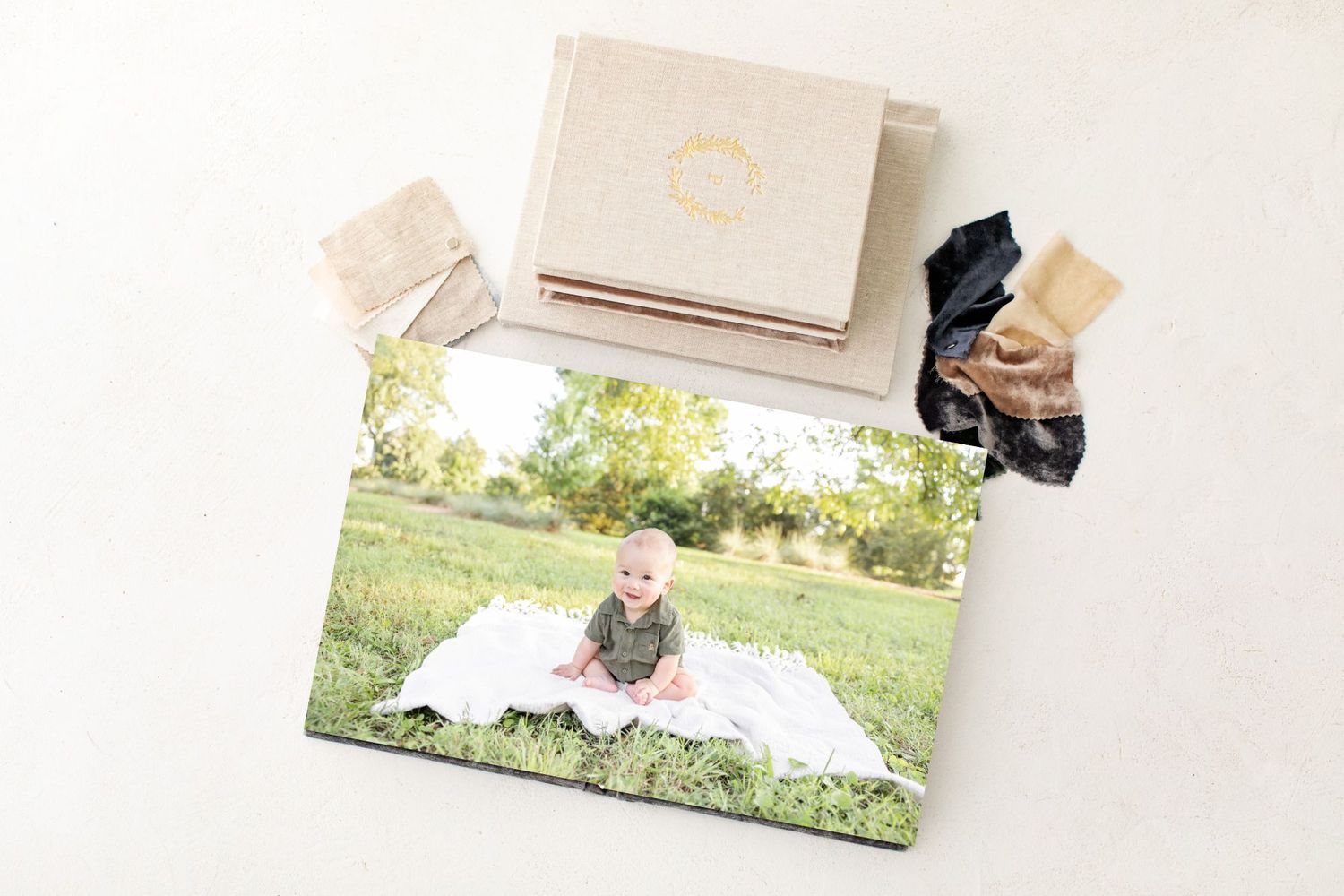 Baby photo displayed in a linen heirloom album with fabric swatches on a neutral background by Columbus, GA family photographer.