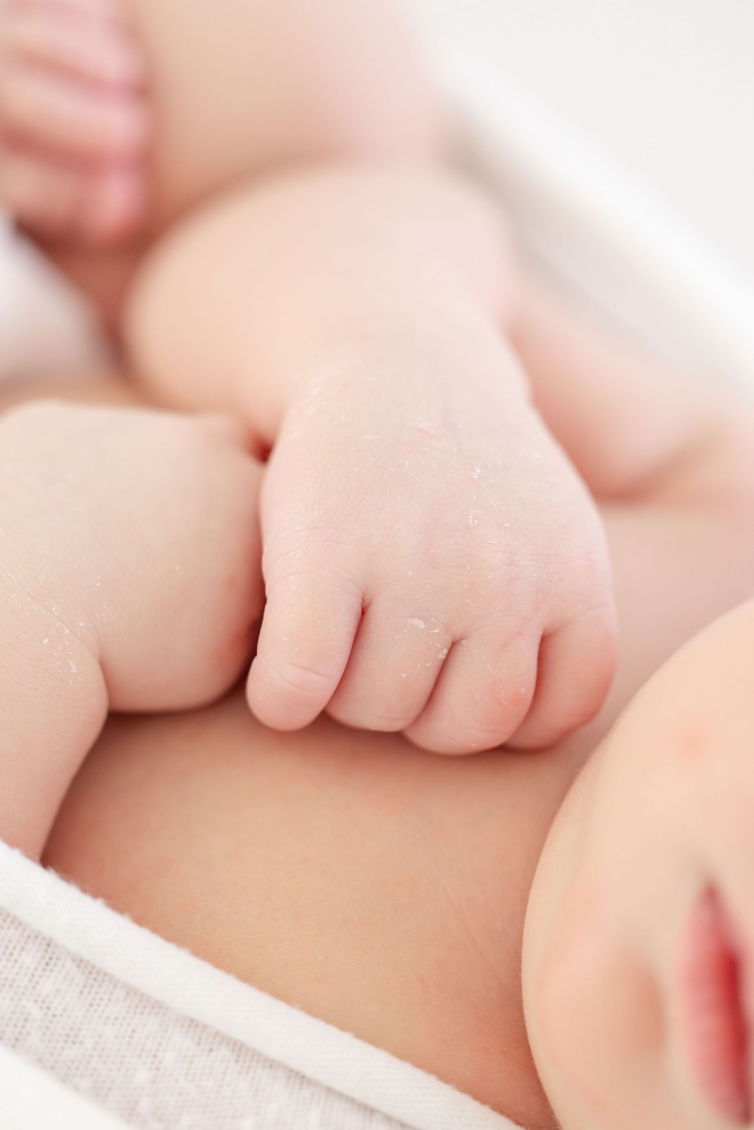 Close up of tiny newborn baby feet and toes wrapped in soft white fabric.