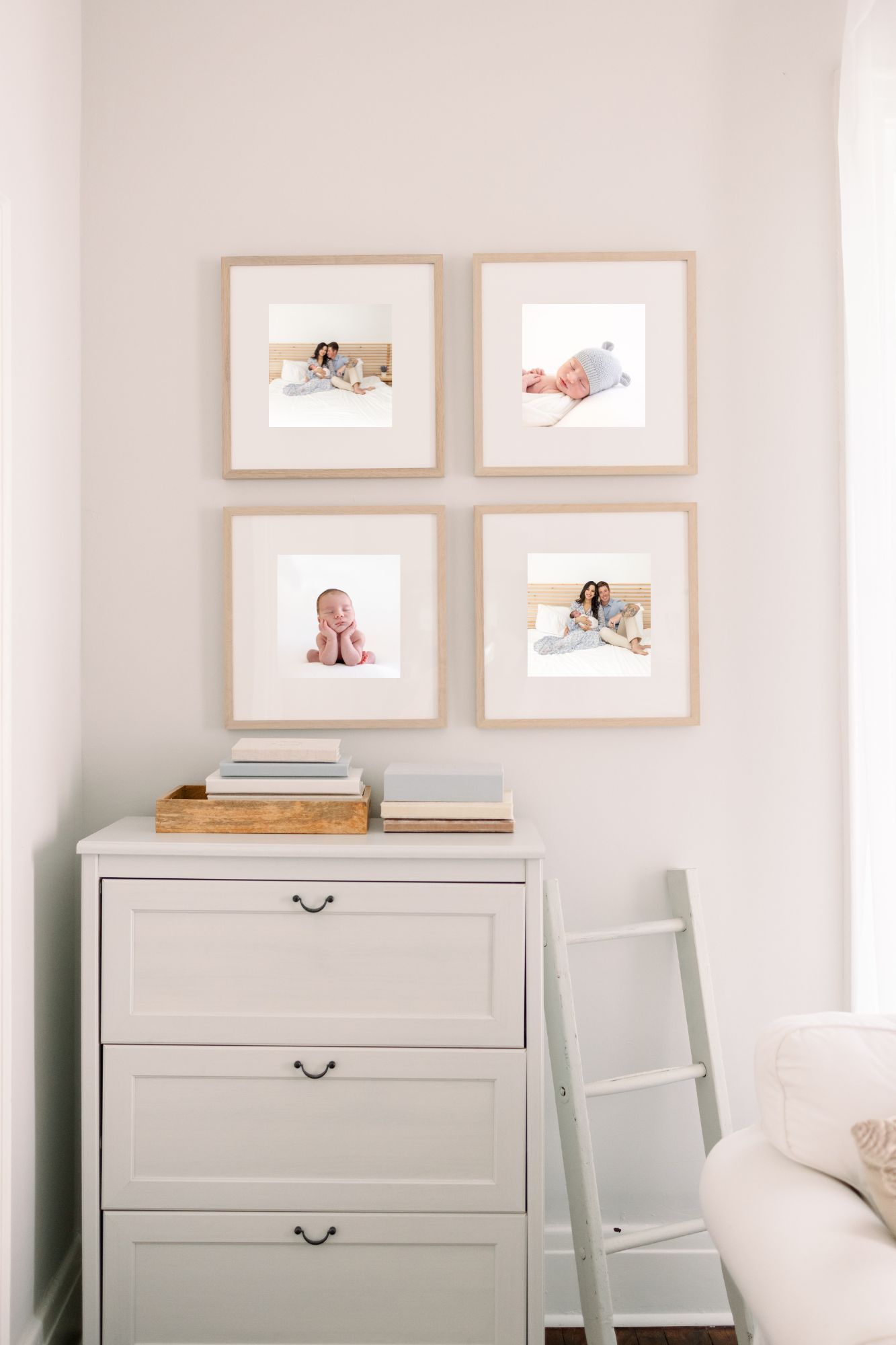 Four framed newborn and baby photos displayed above white dresser in bright minimalist nursery.