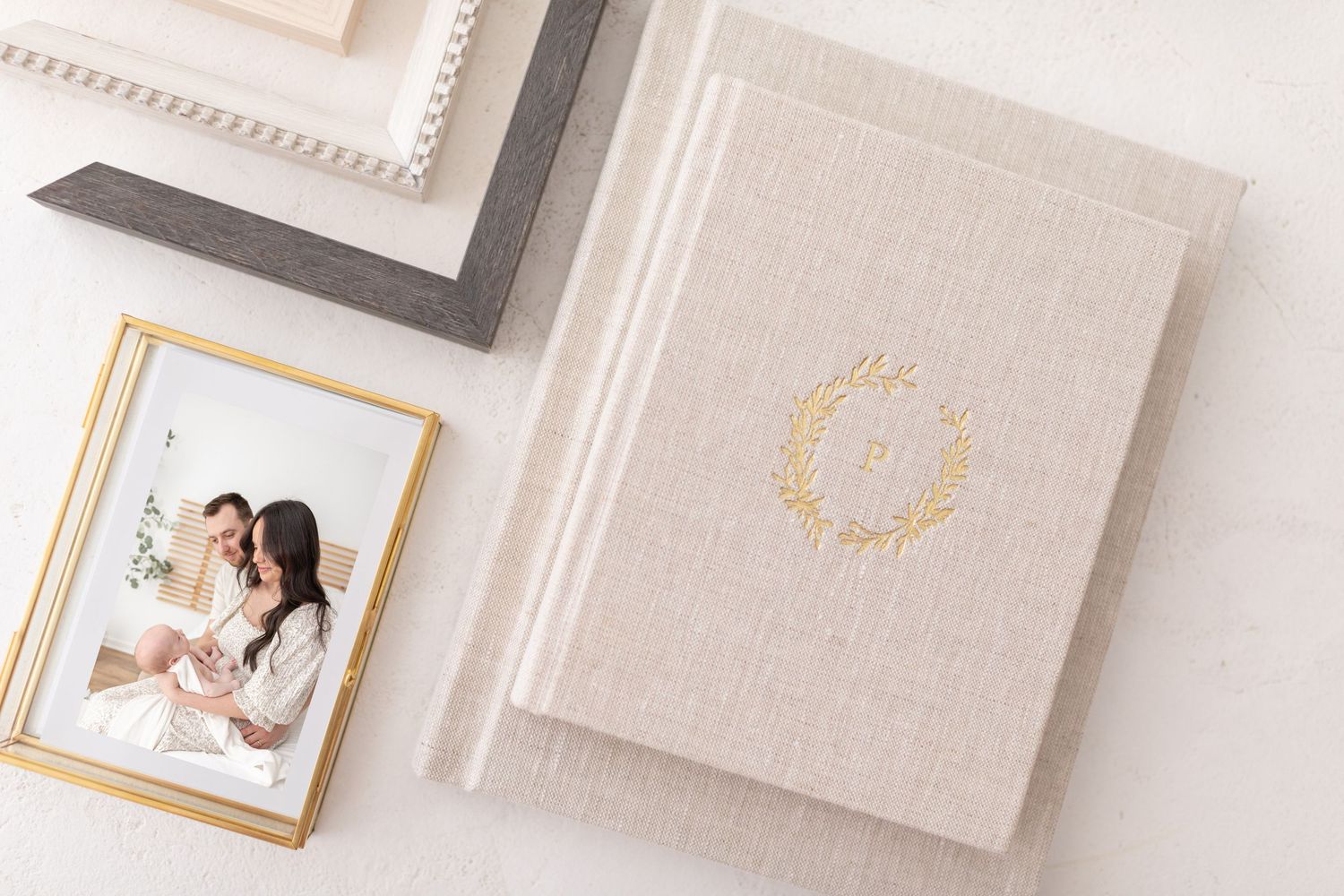 Elegant heirloom album and framed photo in neutral tones with gold monogram details on linen textured surface by Columbus, GA photographer.