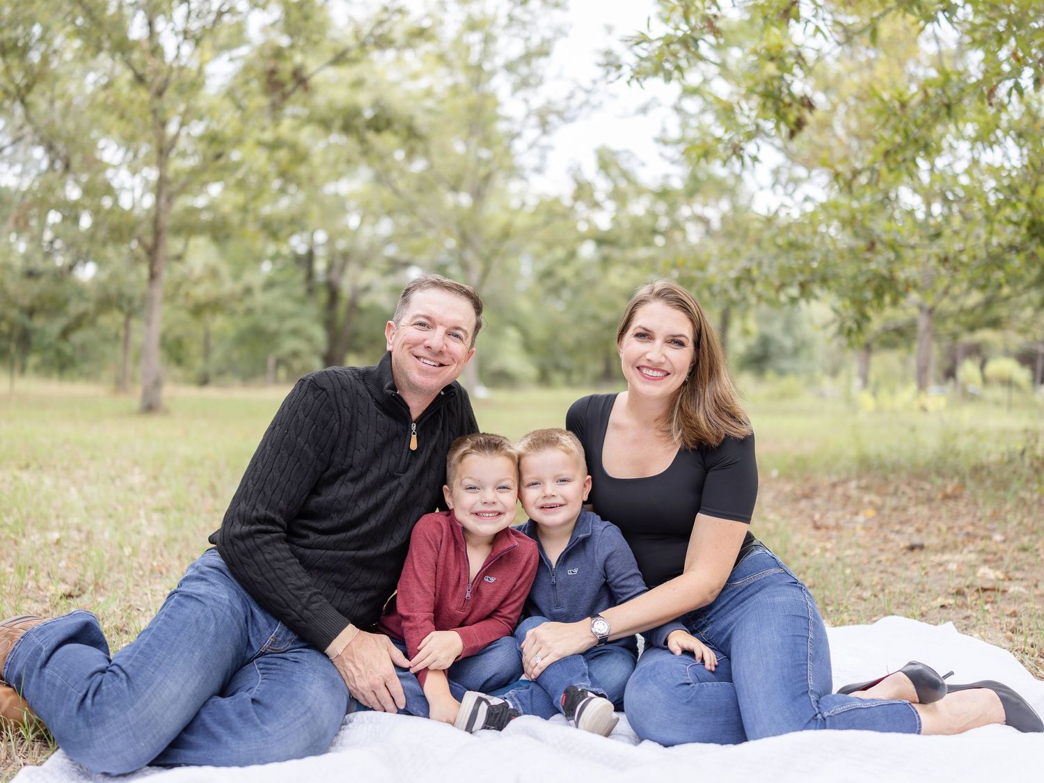 Family relaxing on a white blanket outside during their lifestyle family portrait session in Columbus, GA.