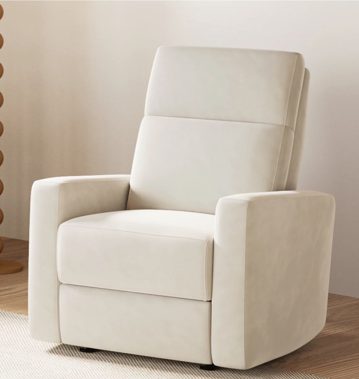 Modern white upholstered recliner chair with clean lines and padded armrests against a neutral wall perfect for a nursery.