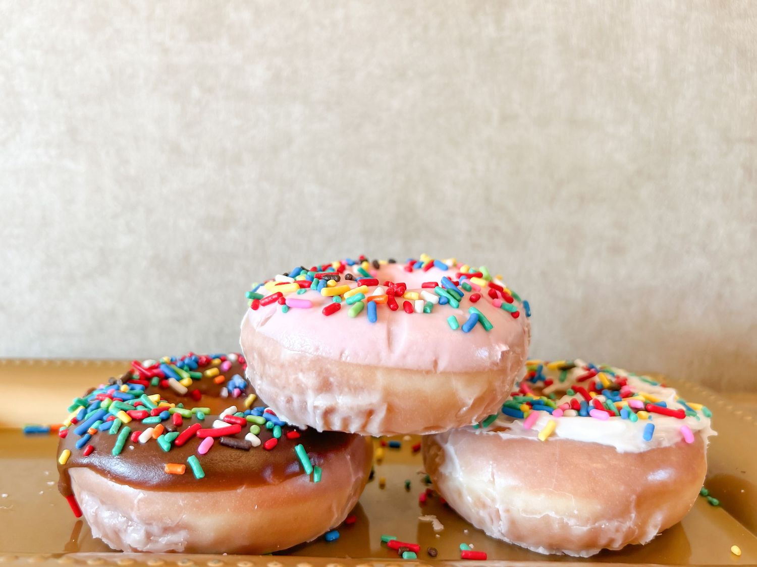 Pink frosted donuts with colorful sprinkles arranged in a row on a light colored surface. best donuts in Columbus, GA