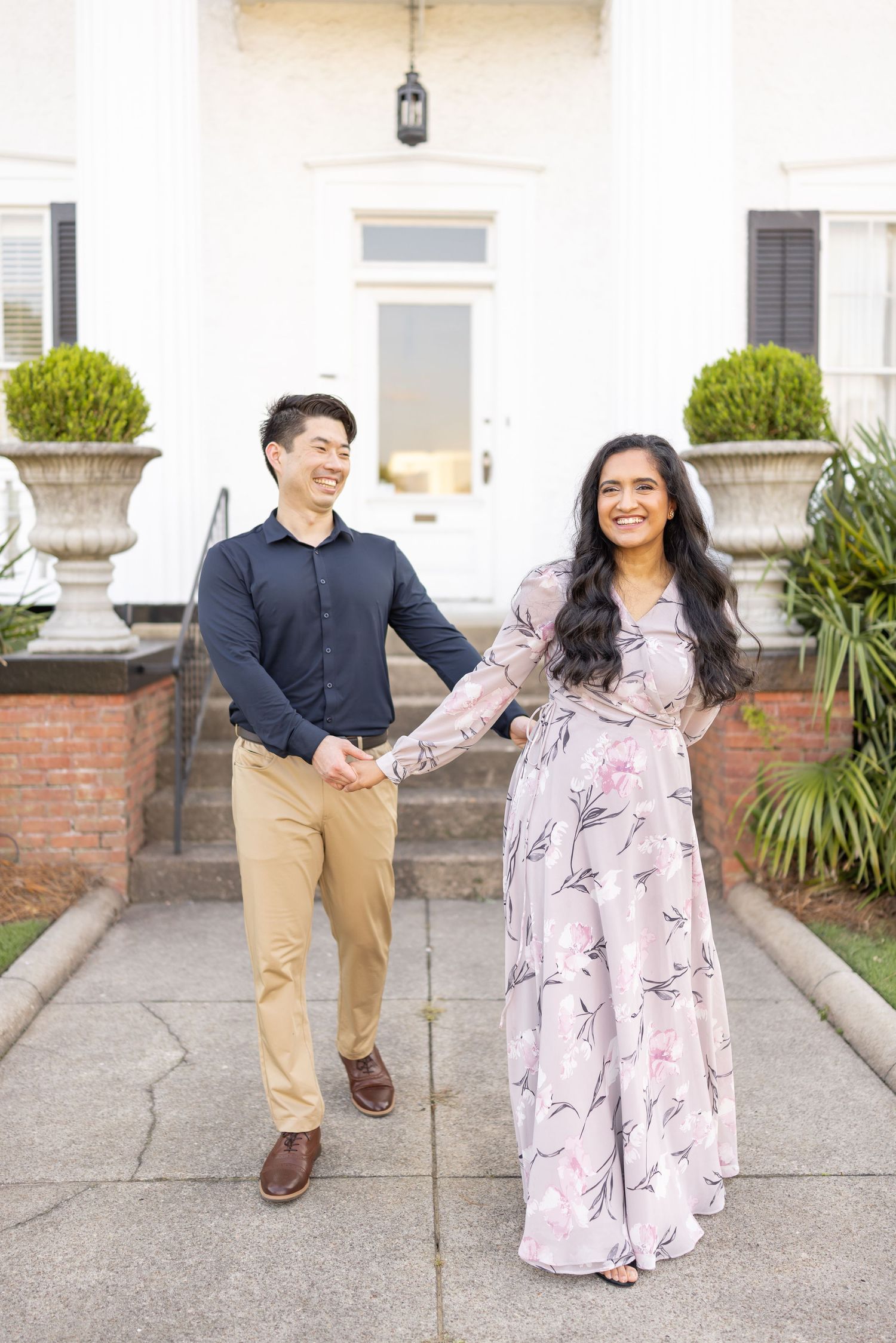 A couple shares a playful moment outdoors in front of a white building during their Columbus, GA family photography session.