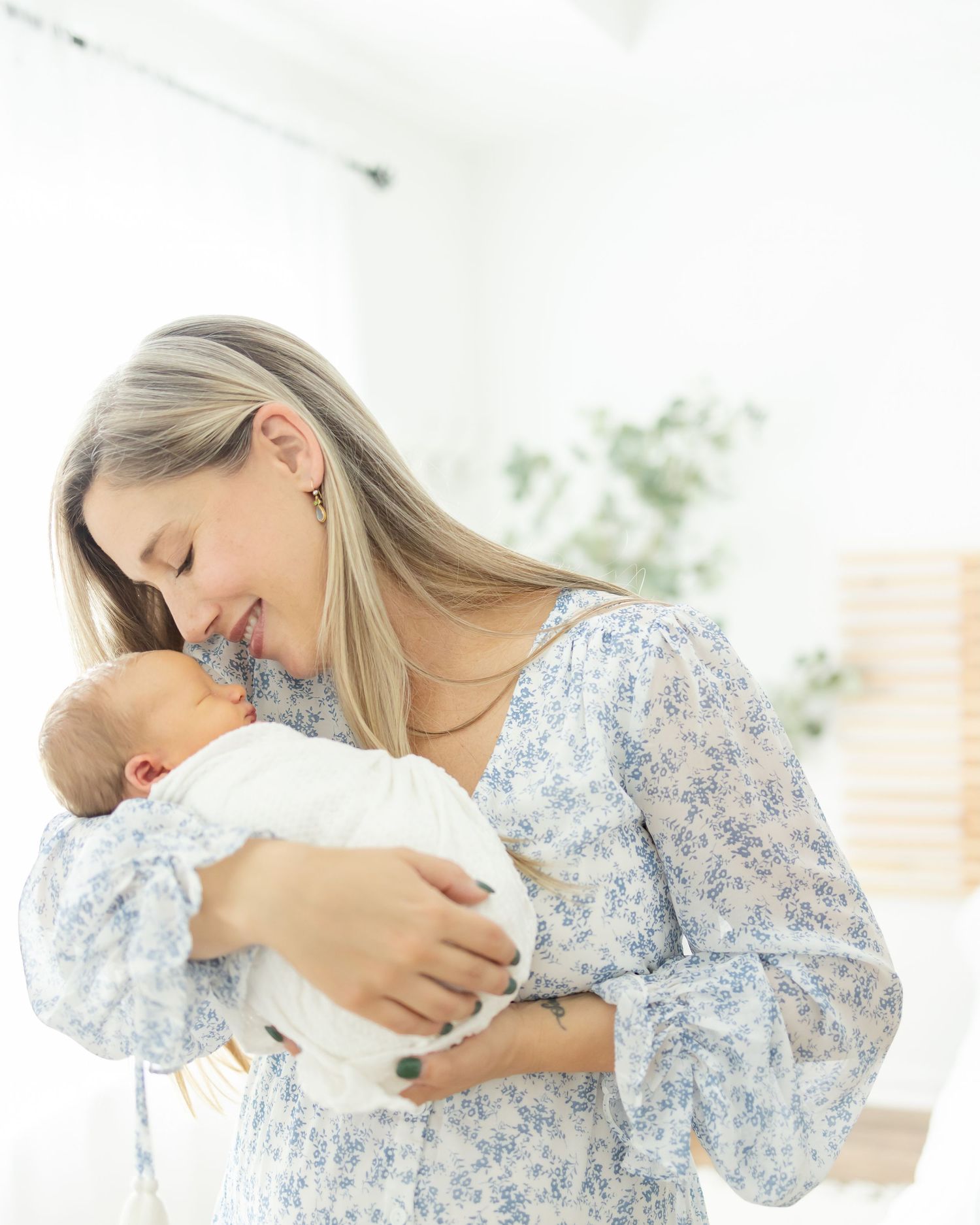 A mother in a floral dress cradles and bonds with her newborn baby by Columbus, GA newborn photographer.