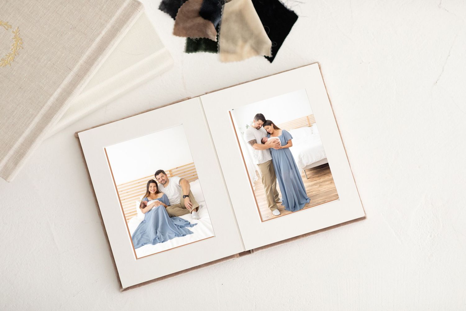 Open photo album displaying two family portraits of a couple in blue dress with baby, on white background.
