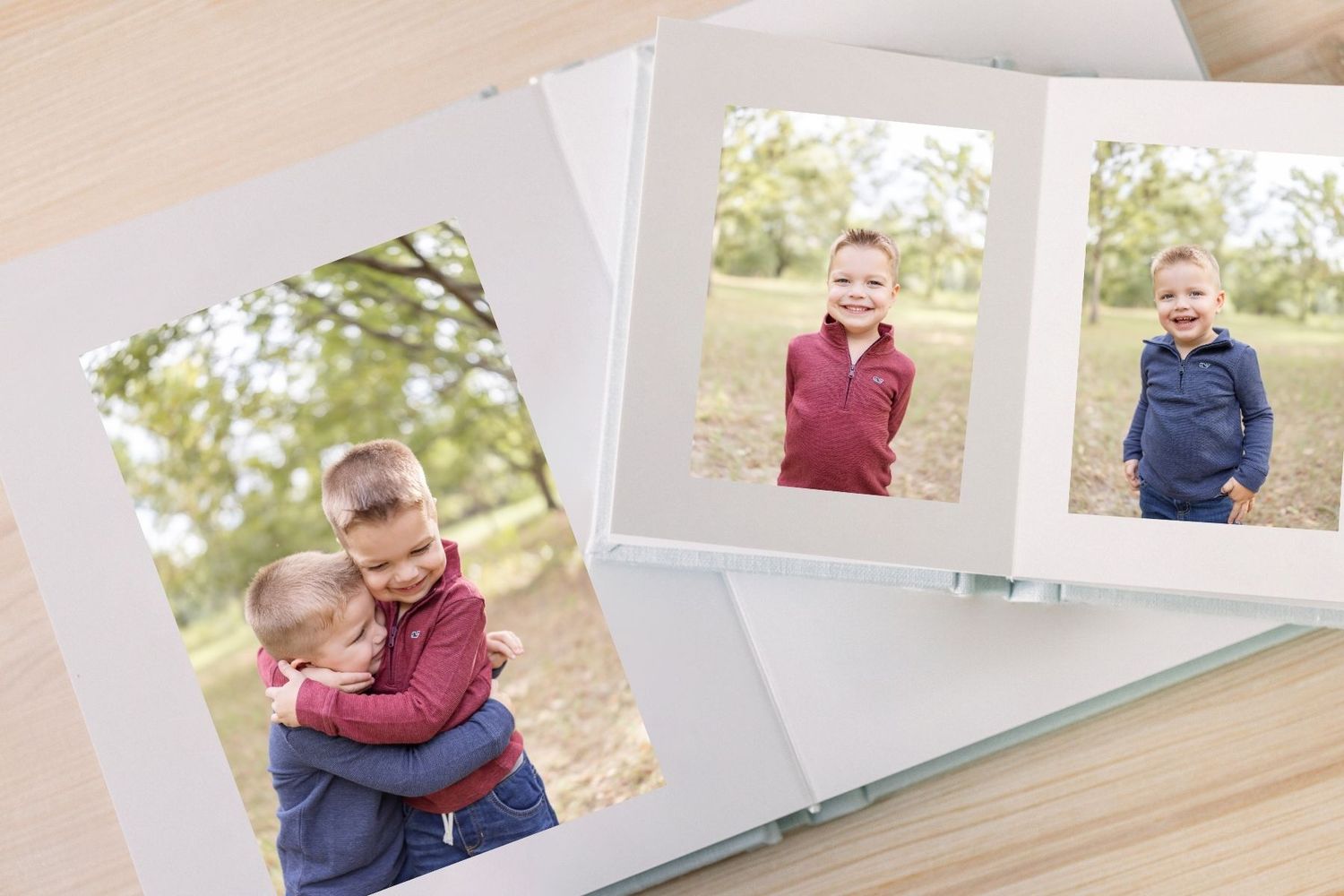 Two custom photo books displaying portraits of young boys outdoors, arranged on a wooden surface by Columbus, GA Family Photographer.