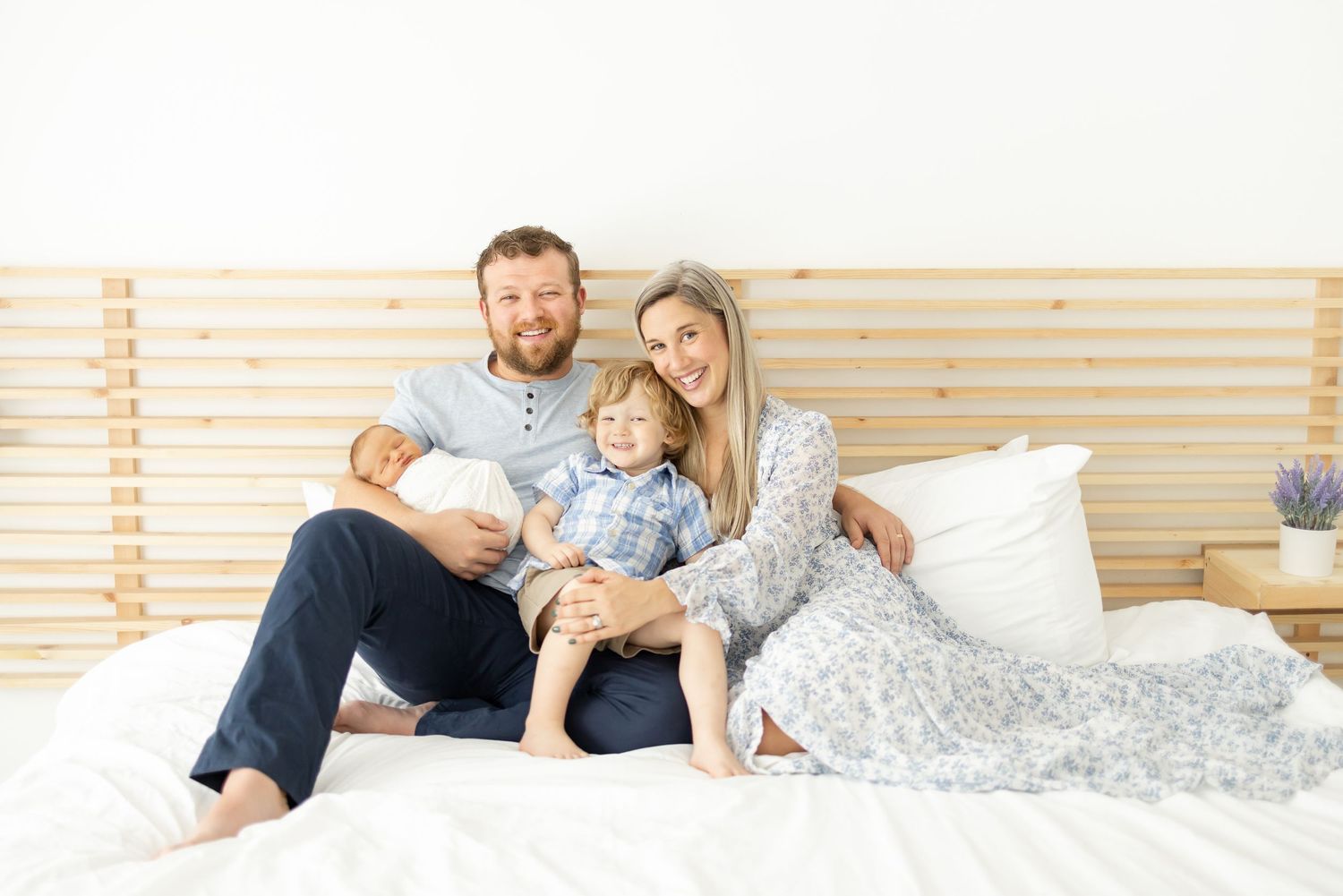 Family relaxing together on a cozy bed at their Columbus, GA Newborn Portrait session.