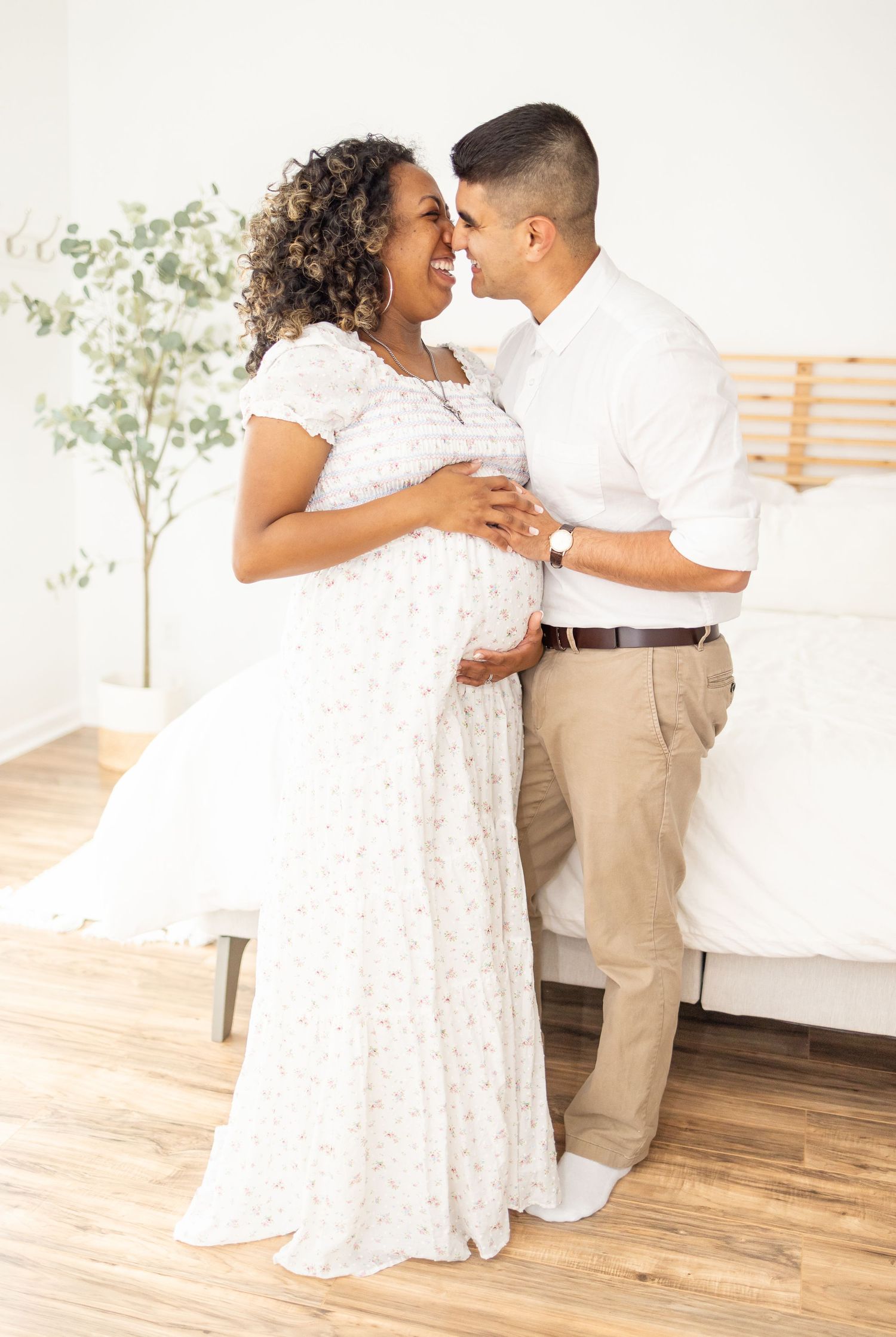 A couple in elegant white and khaki attire share an intimate dance moment on a wooden deck outdoors.