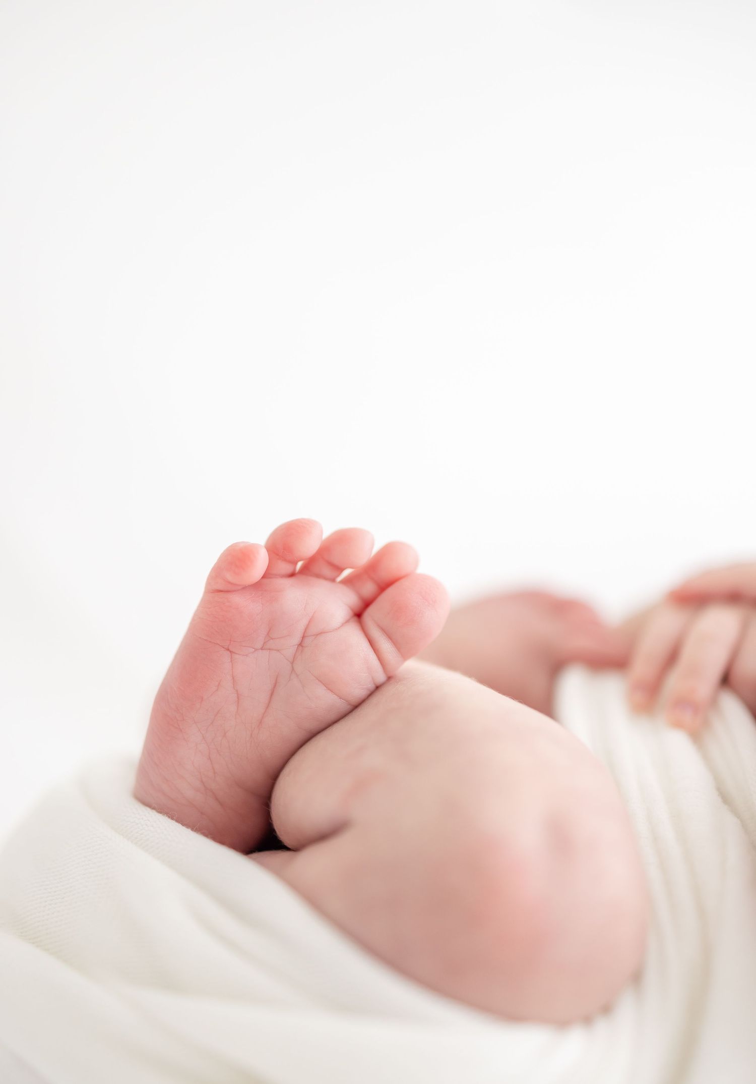 Close-up view of tiny newborn baby feet against a soft white background by Columbus, GA newborn photographer.