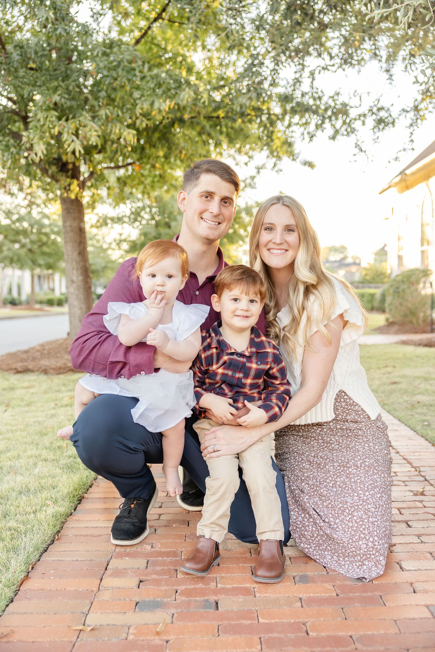 Family sitting together on brick steps at sunset in coordinating creams and maroons for their holiday family photos in Columbus, GA.