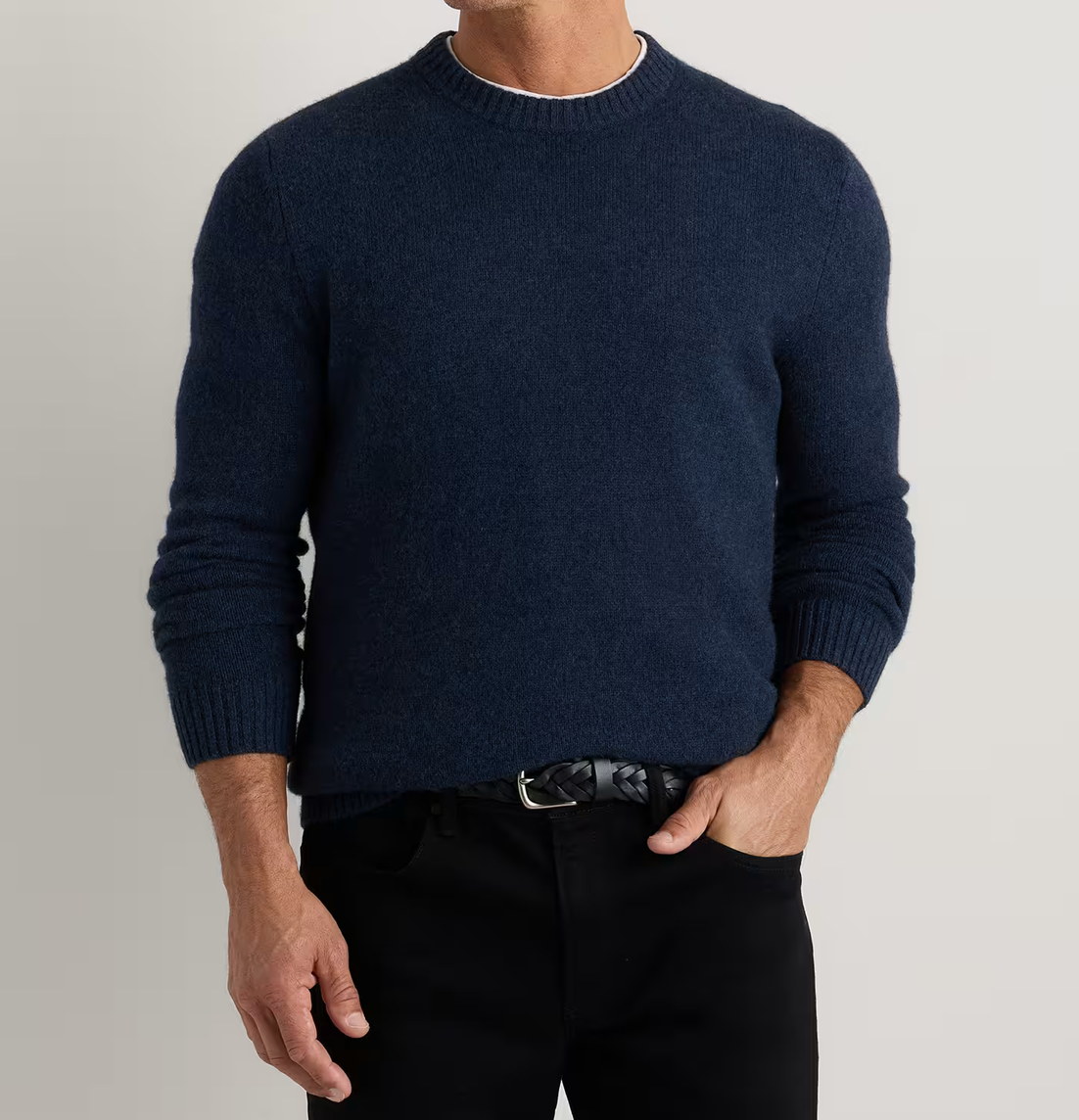Men's navy blue crewneck knit sweater paired with black jeans and a leather belt.