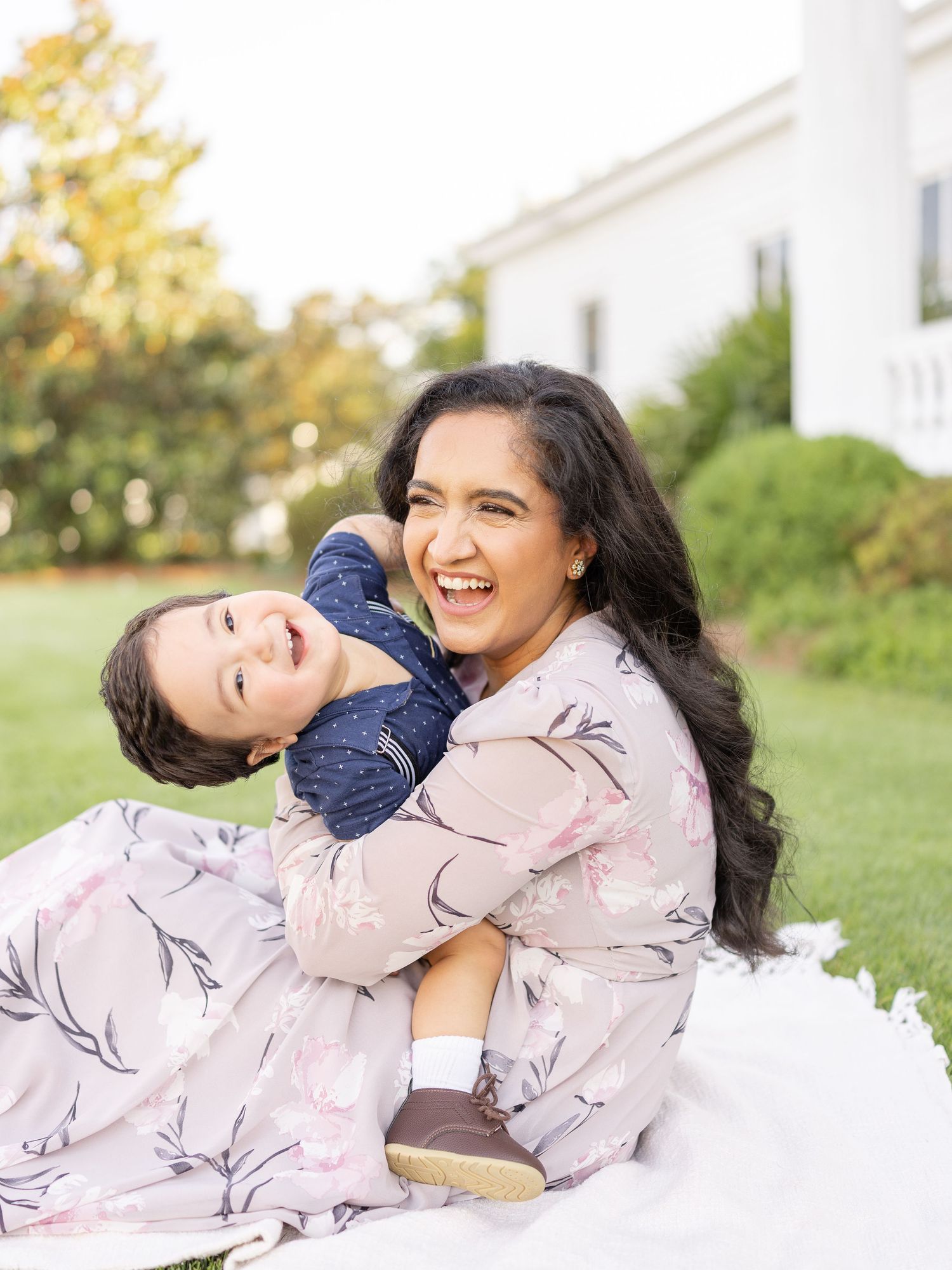 Mother and child playing on the grass outdoors sharing joyful laughter in a candid moment during family photography session in Columbus, GA.