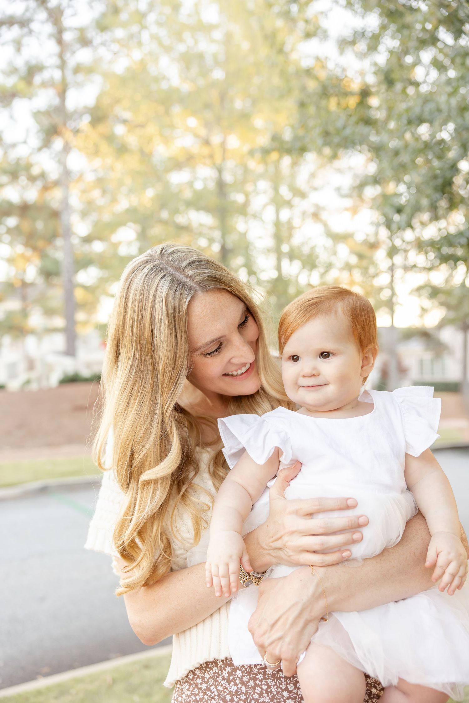 A touching moment shared between a mother and daughter in white clothing outdoors in warm golden light at their fall family photo session