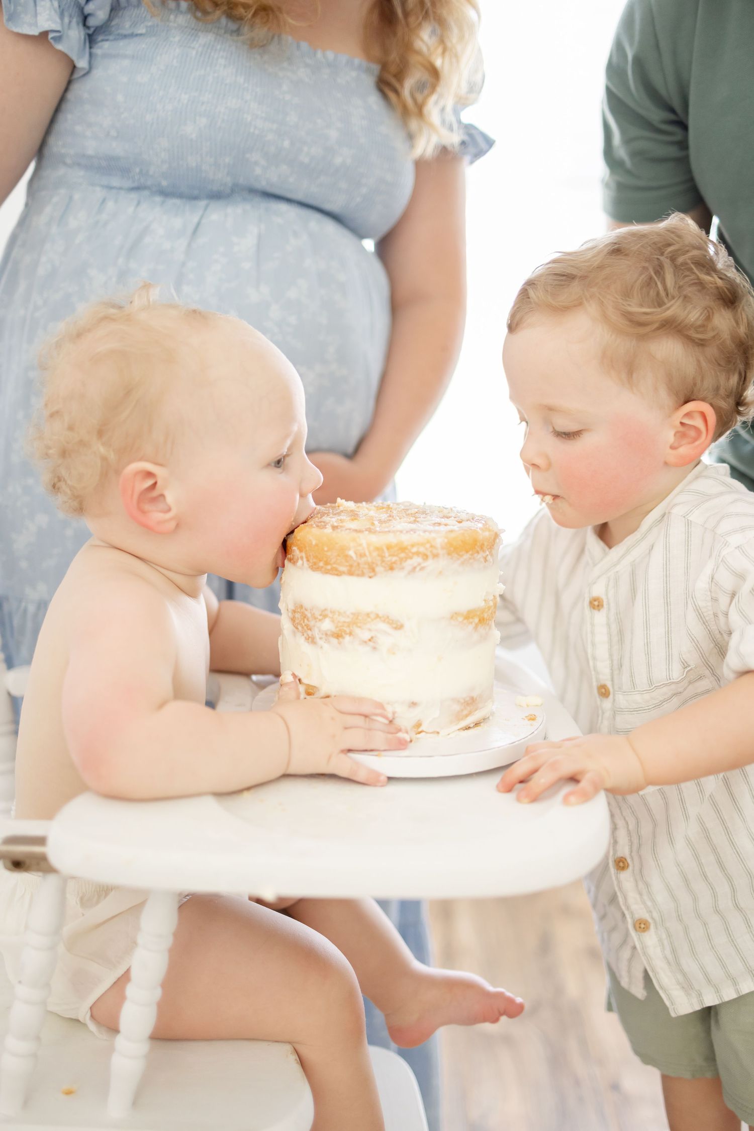 First birthday milestone photoshoot where big brother is helping to eat the birthday cake.