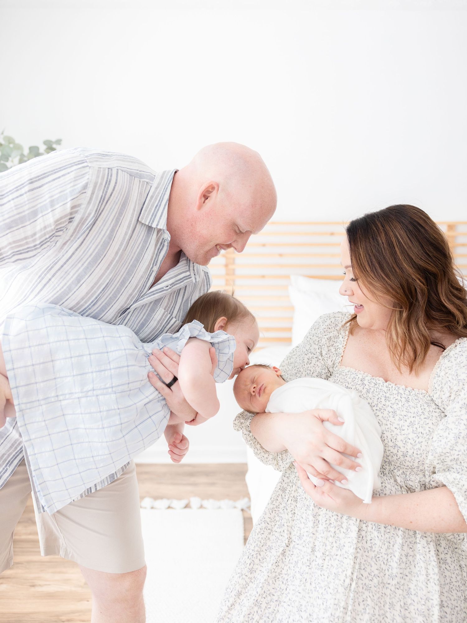 A family in soft blues tones shares a playful moment at their Columbus, GA newborn portrait session.