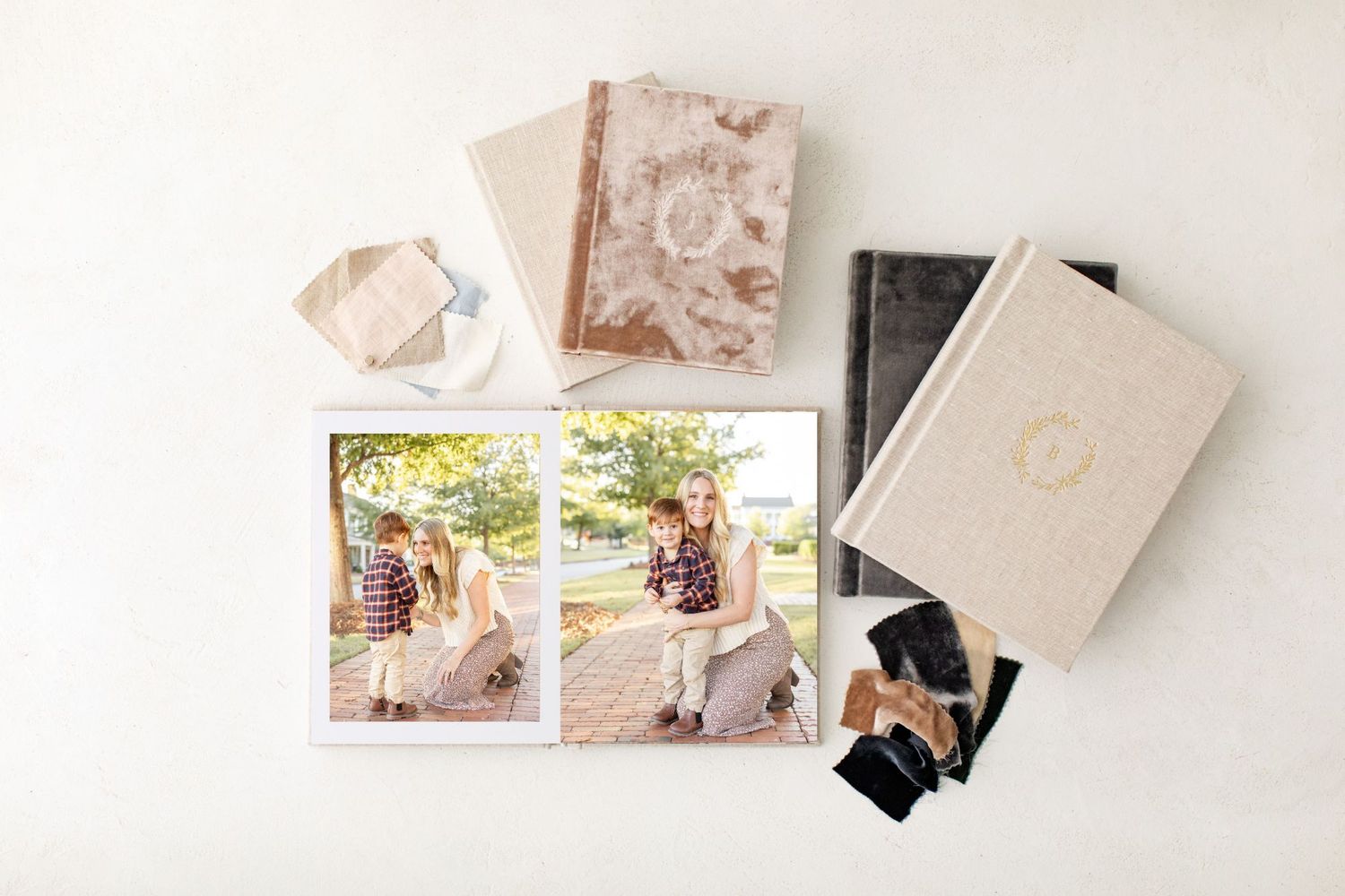 Flat lay of elegant photo albums, one open and showing photos of a mother and her son by Columbus, GA portrait photographer.