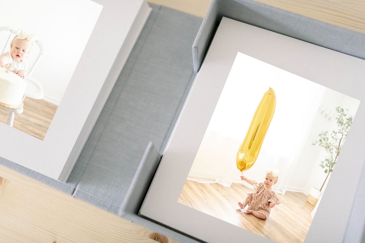 Two open photo albums displaying baby portraits, one with a child on white background and one with a baby near a yellow surfboard.