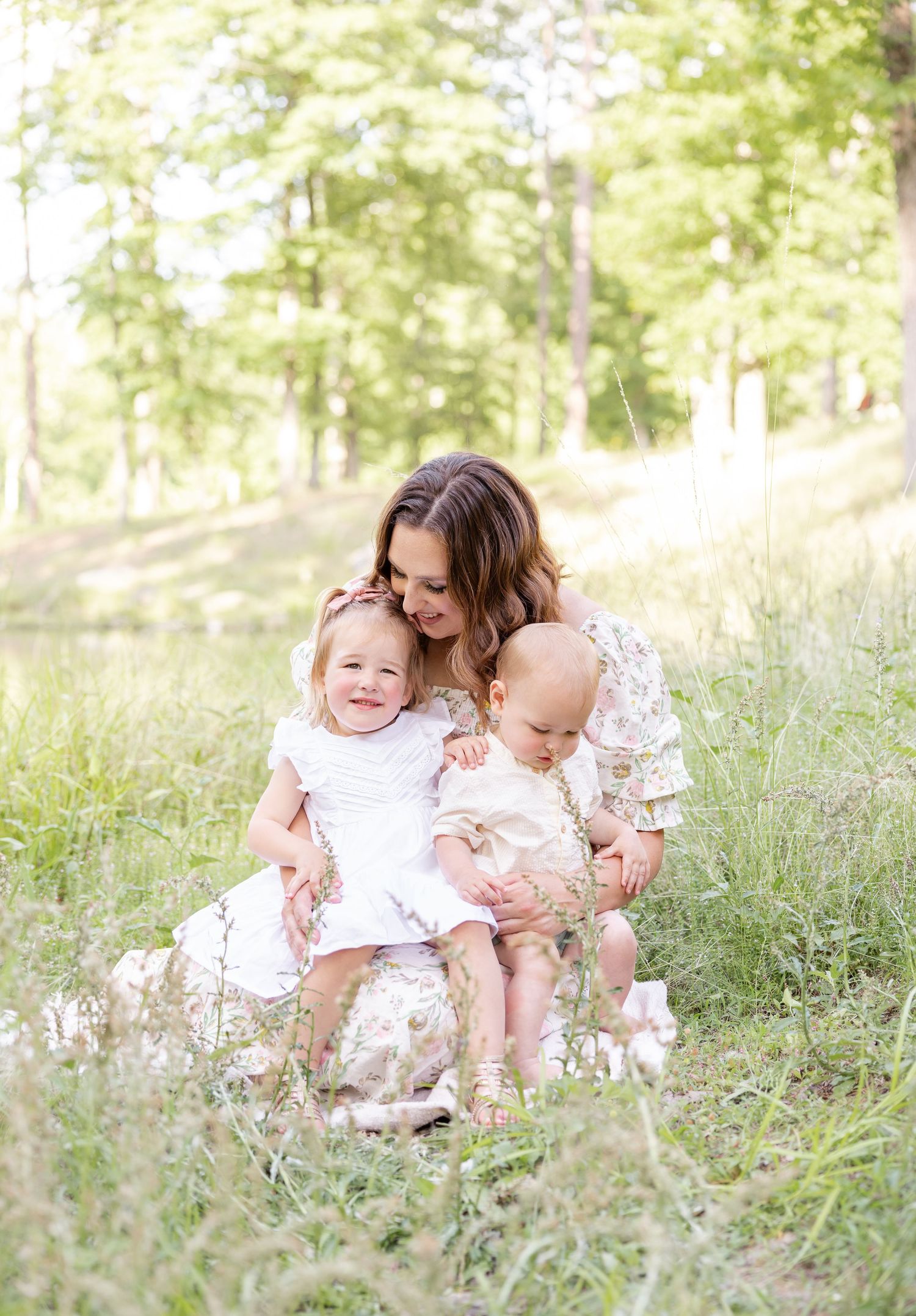 A touching moment between mom and her two little kids in a soft lit field by a Columbus, GA photographer.