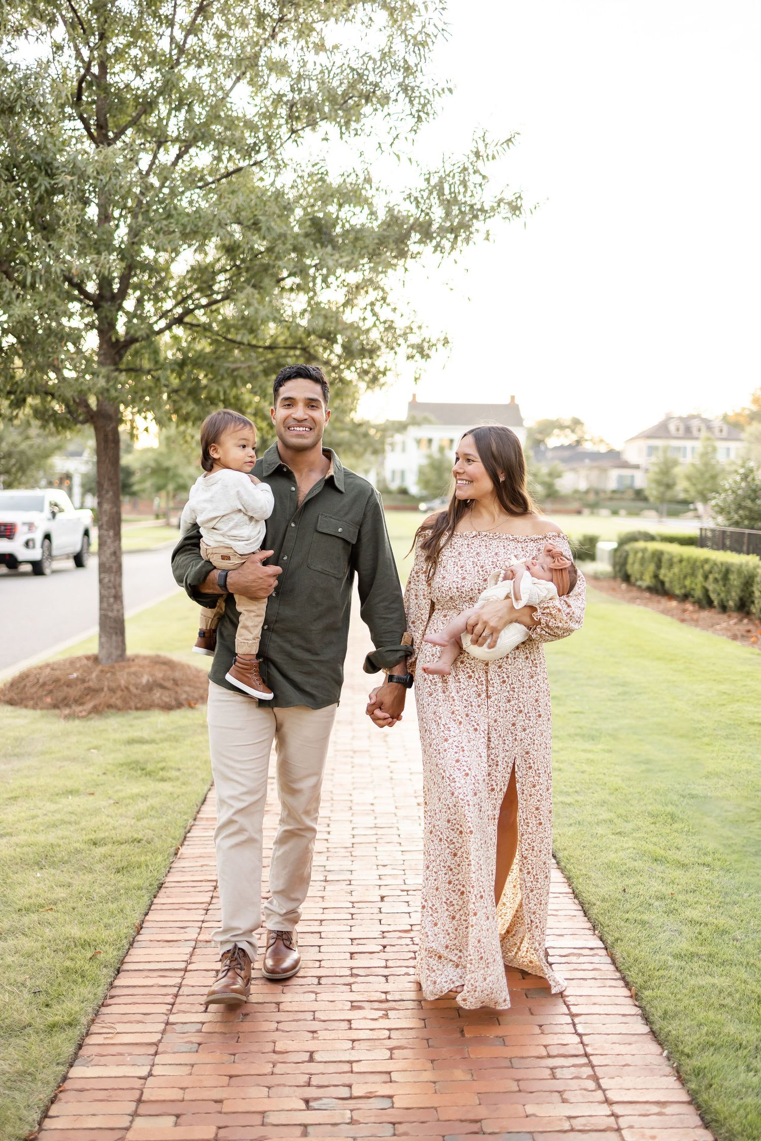 A family walks hand in hand down a brick pathway during golden hour at Old Town Columbus with their Columbus GA family photographer.