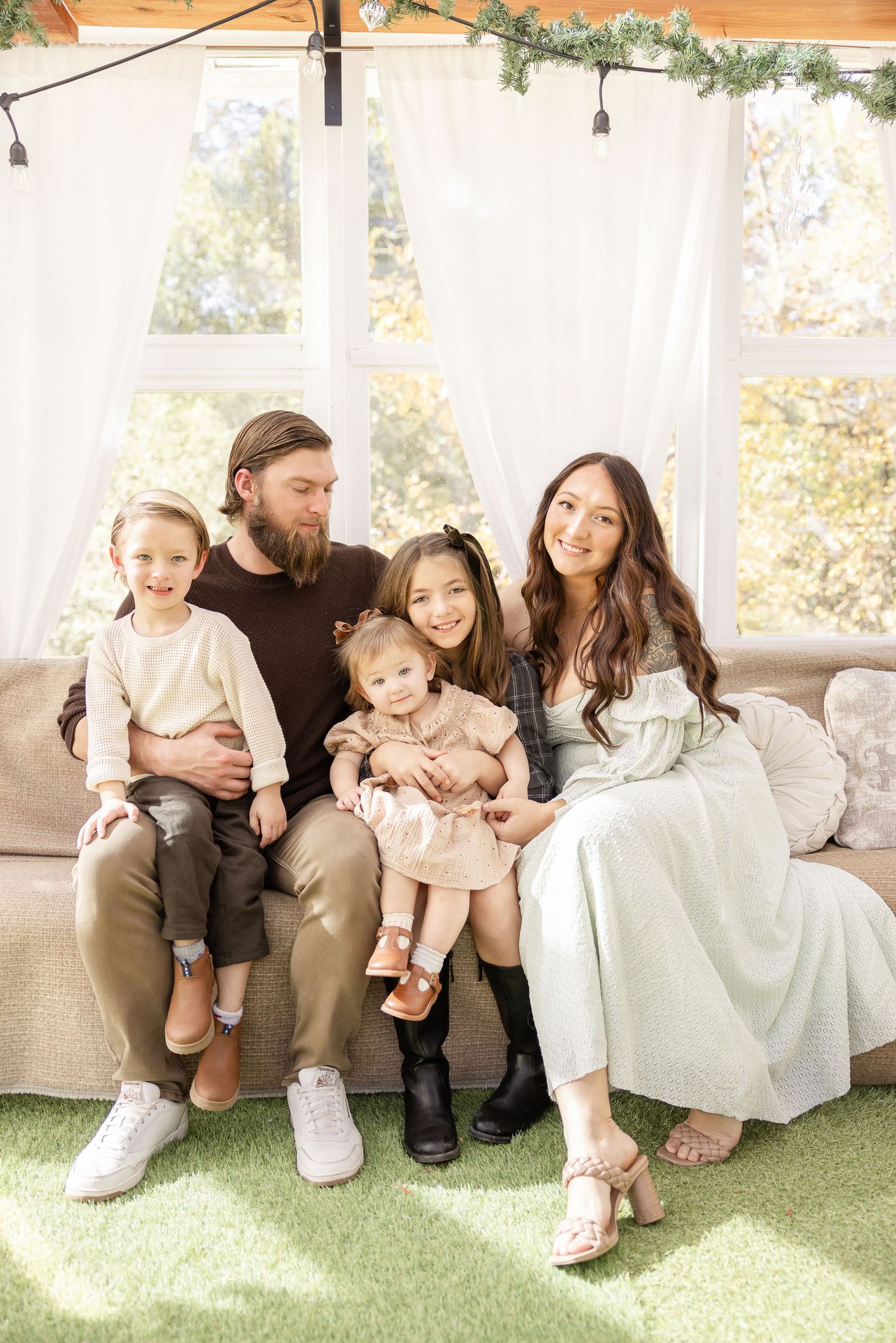 A family of 5 smiles at their Columbus, GA photographer at their fall greenhouse family portrait session.