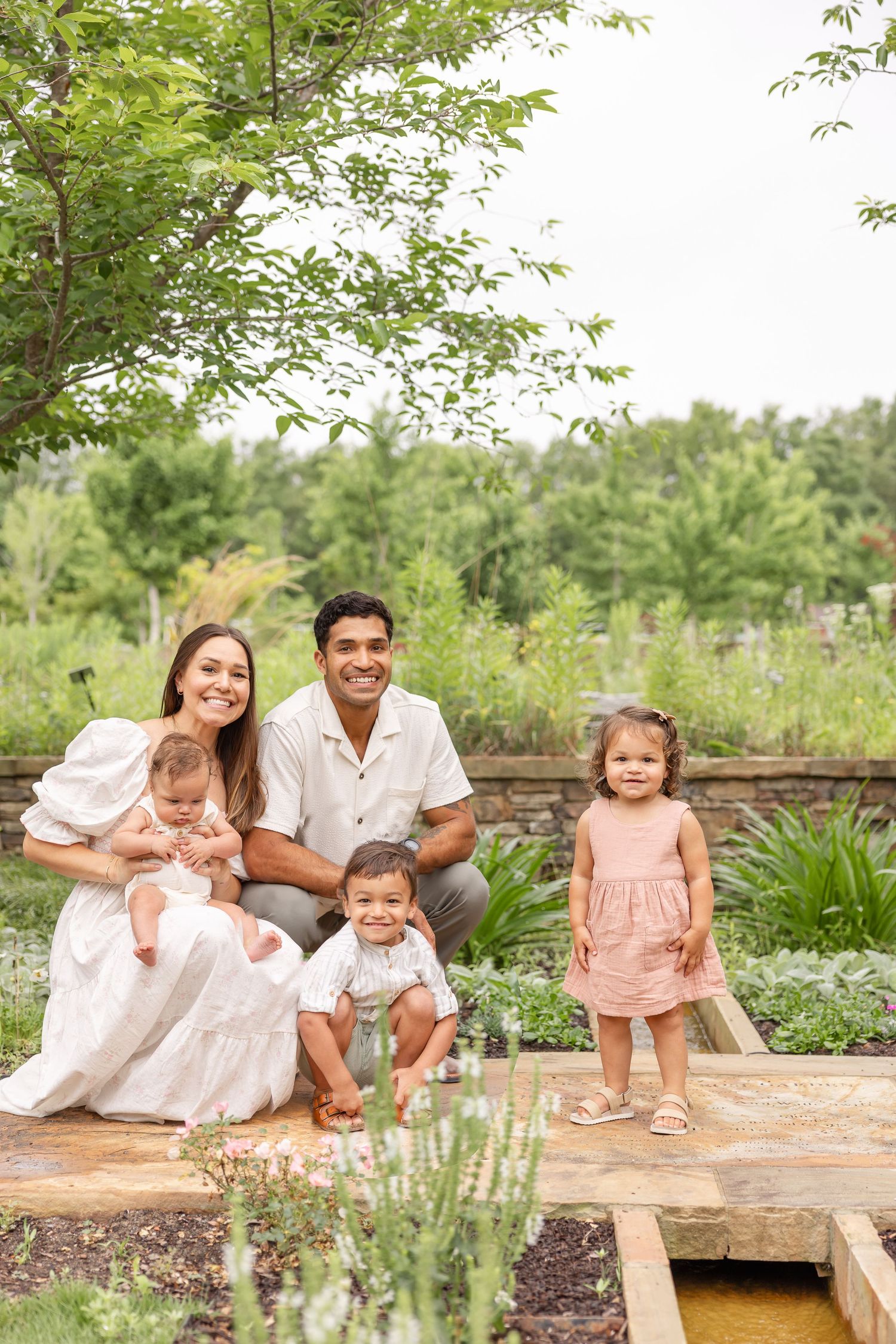 Family of 5 gathers together in a lush green garden for their outdoor family photography session in Columbus, GA.