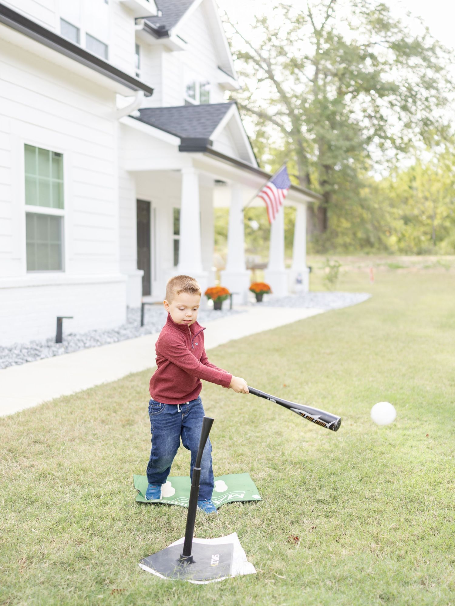 A small child plays baseball in front of his home at his Columbus, GA lifestyle family portrait session by Columbus, GA photographer.