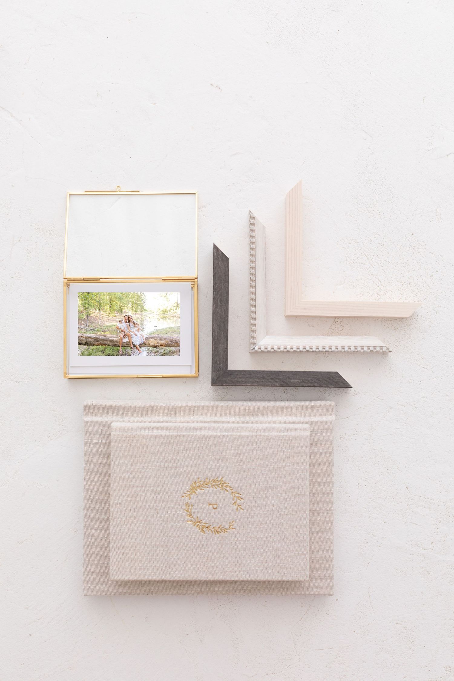 Elegant family albums, gold glass photo box, and frame corner samples arranged on a white surface.
