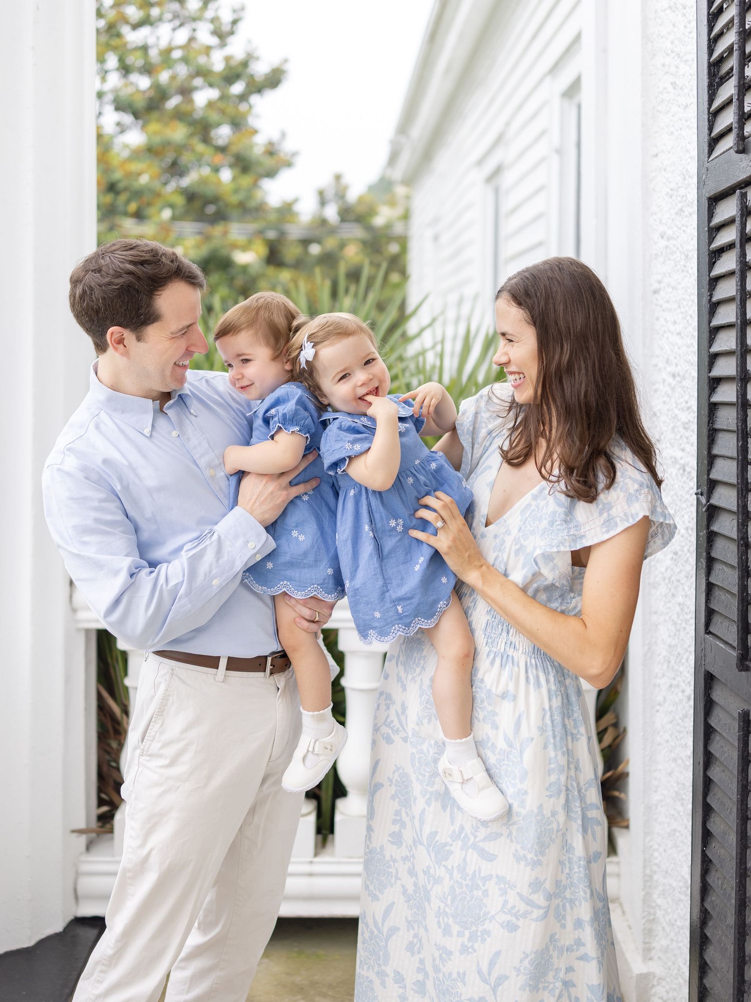 A family in soft coordinating blue and white outfits poses outdoors at their Columbus, GA family photography session.