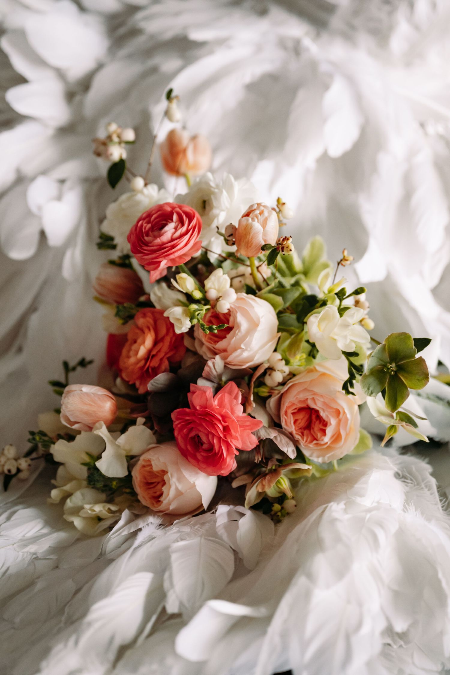 Beautiful wedding bouquet with pink roses and white flowers resting on white fabric in soft natural light.