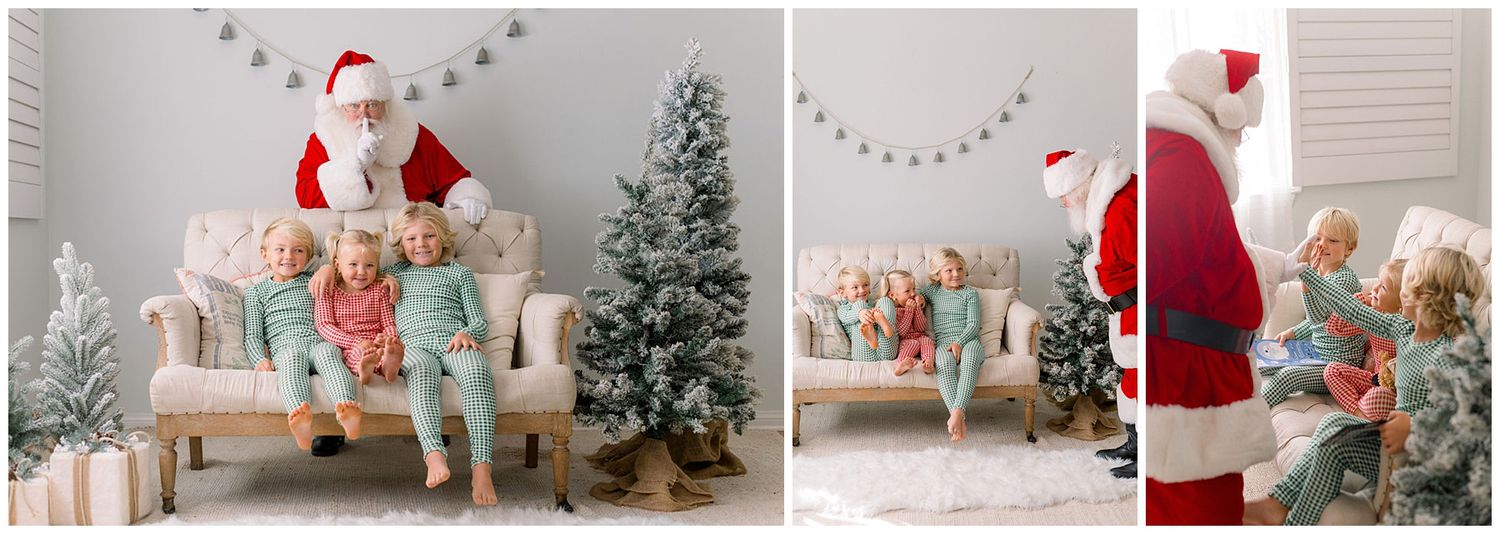 Santa Claus sits with two young children in matching pajamas near a flocked Christmas tree in a bright studio setting.