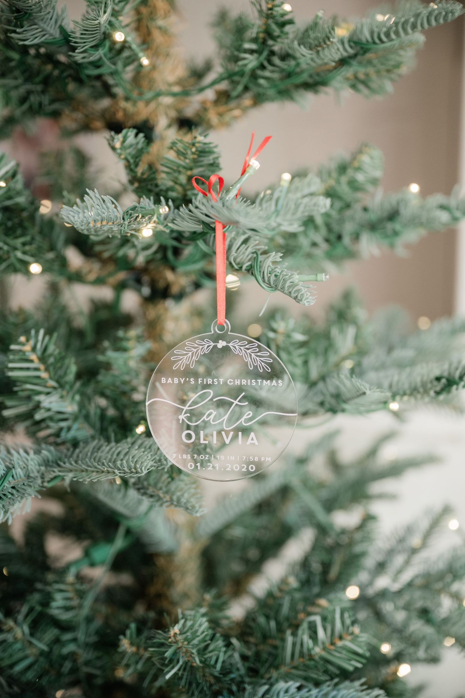 Personalized baby first Christmas clear acrylic ornament on a Christmas tree.