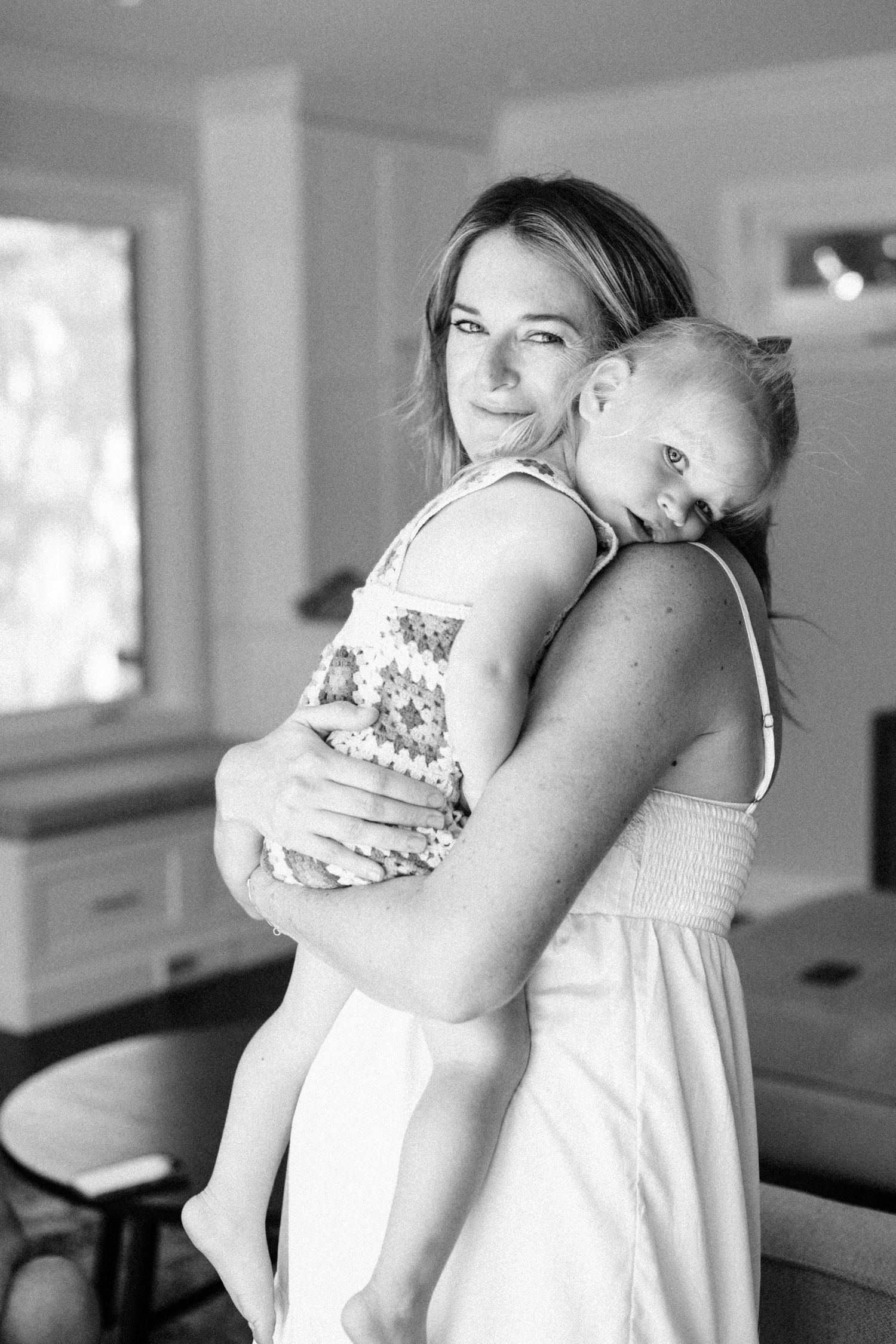 Black and white photo of mother holding sleeping toddler child indoors.