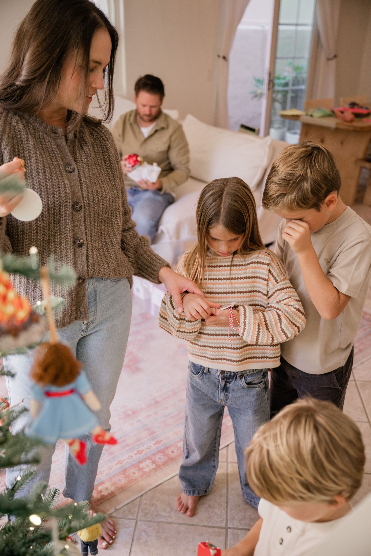 Family decorating Christmas tree together in a cozy living room setting.