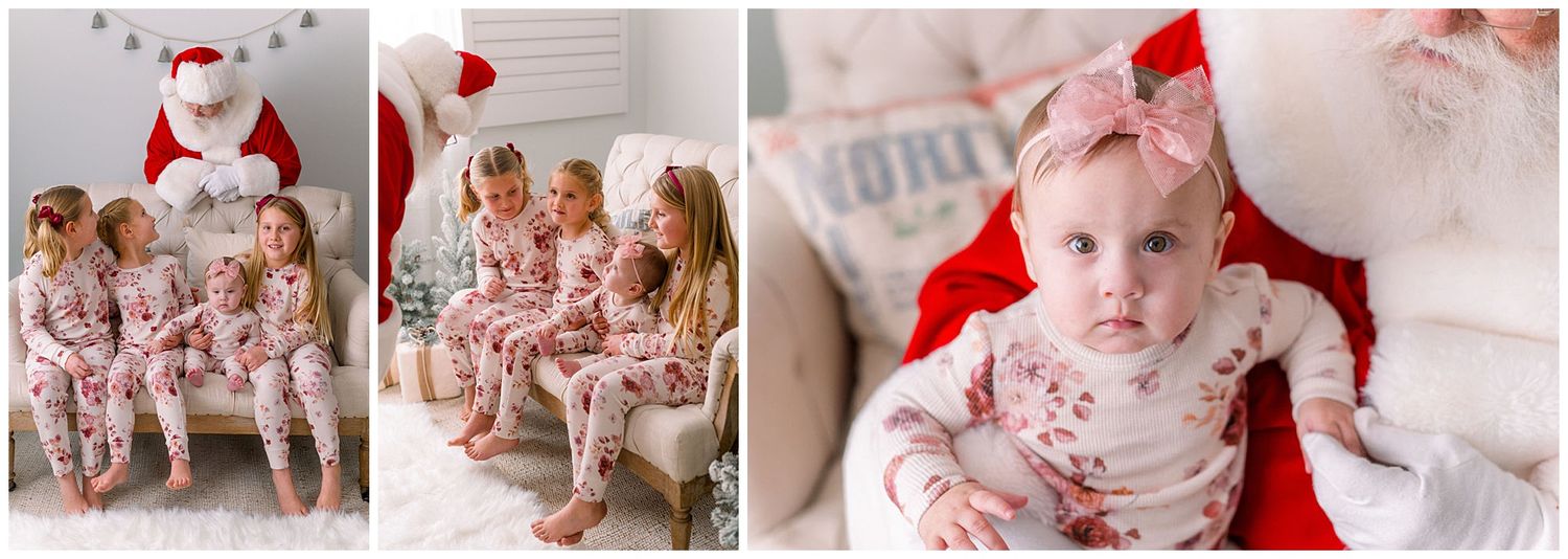 Three little girls in matching floral pajamas sit with Santa, while a baby in a bow headband is held by Santa Claus.