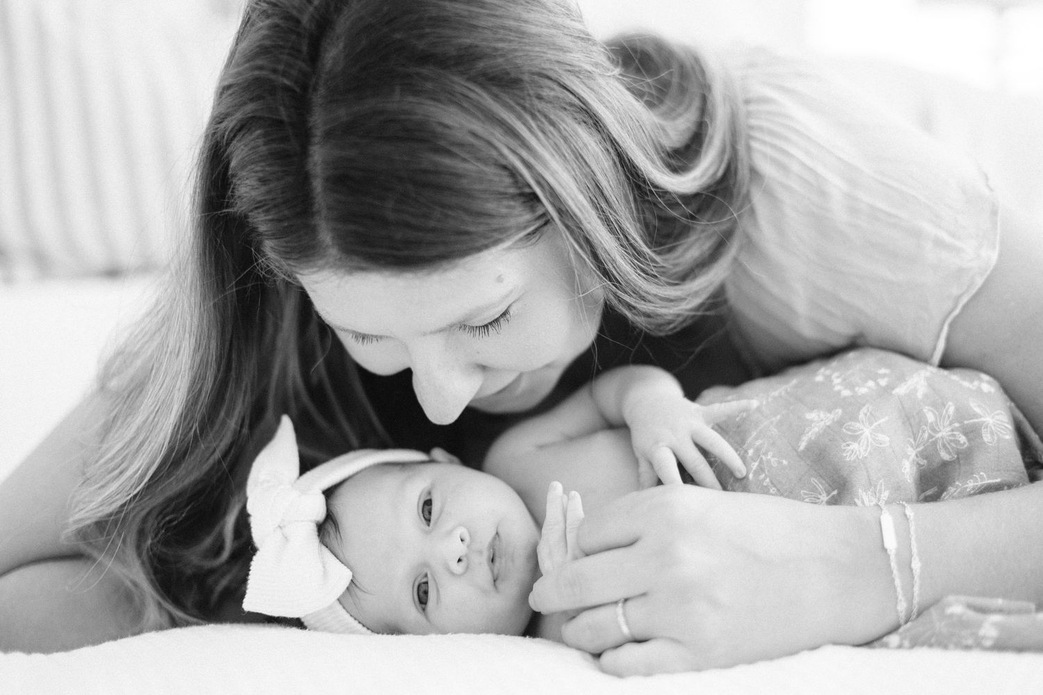 Mother tenderly gazing at her newborn baby in black and white portrait photo.