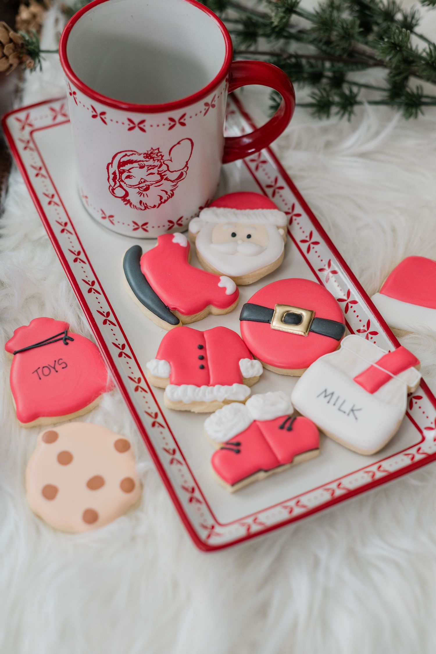 Festive Santa-themed decorated sugar cookies and a Santa mug arranged on a red and white holiday serving tray.