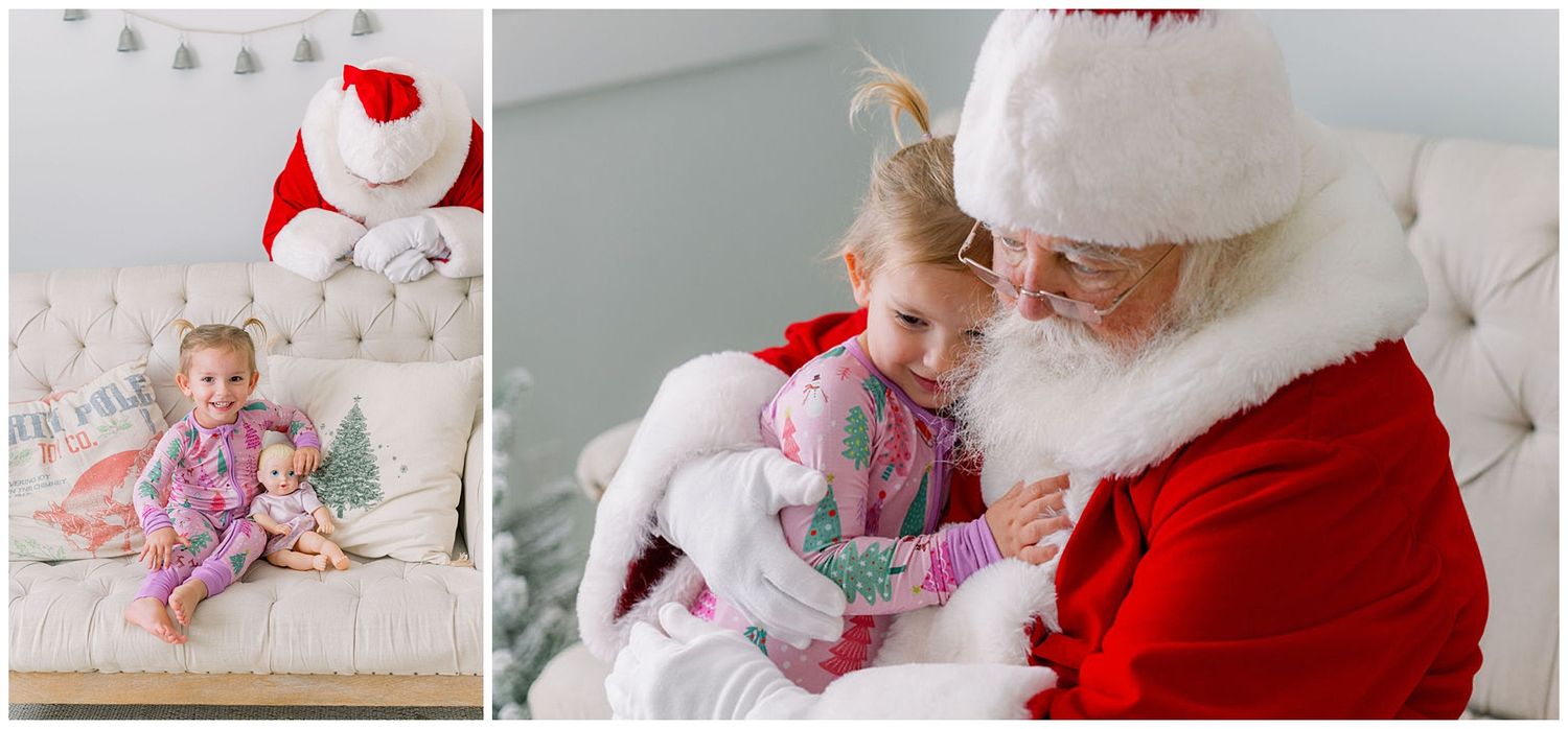 A young girl in pajamas sits with Santa Claus on a white tufted sofa during a cozy Christmas photo session.