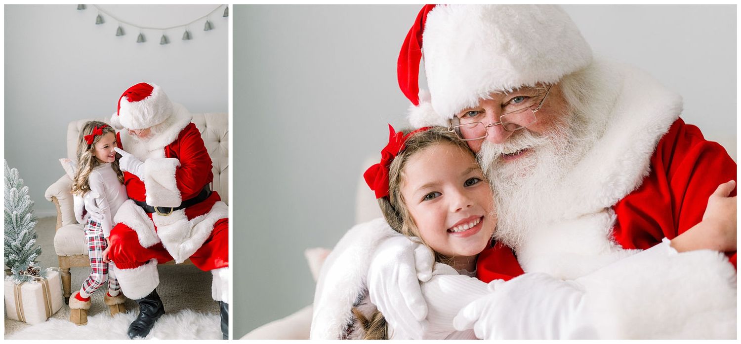 A young girl in holiday pajamas smiles with Santa Claus during a festive Christmas photo session in a bright studio.