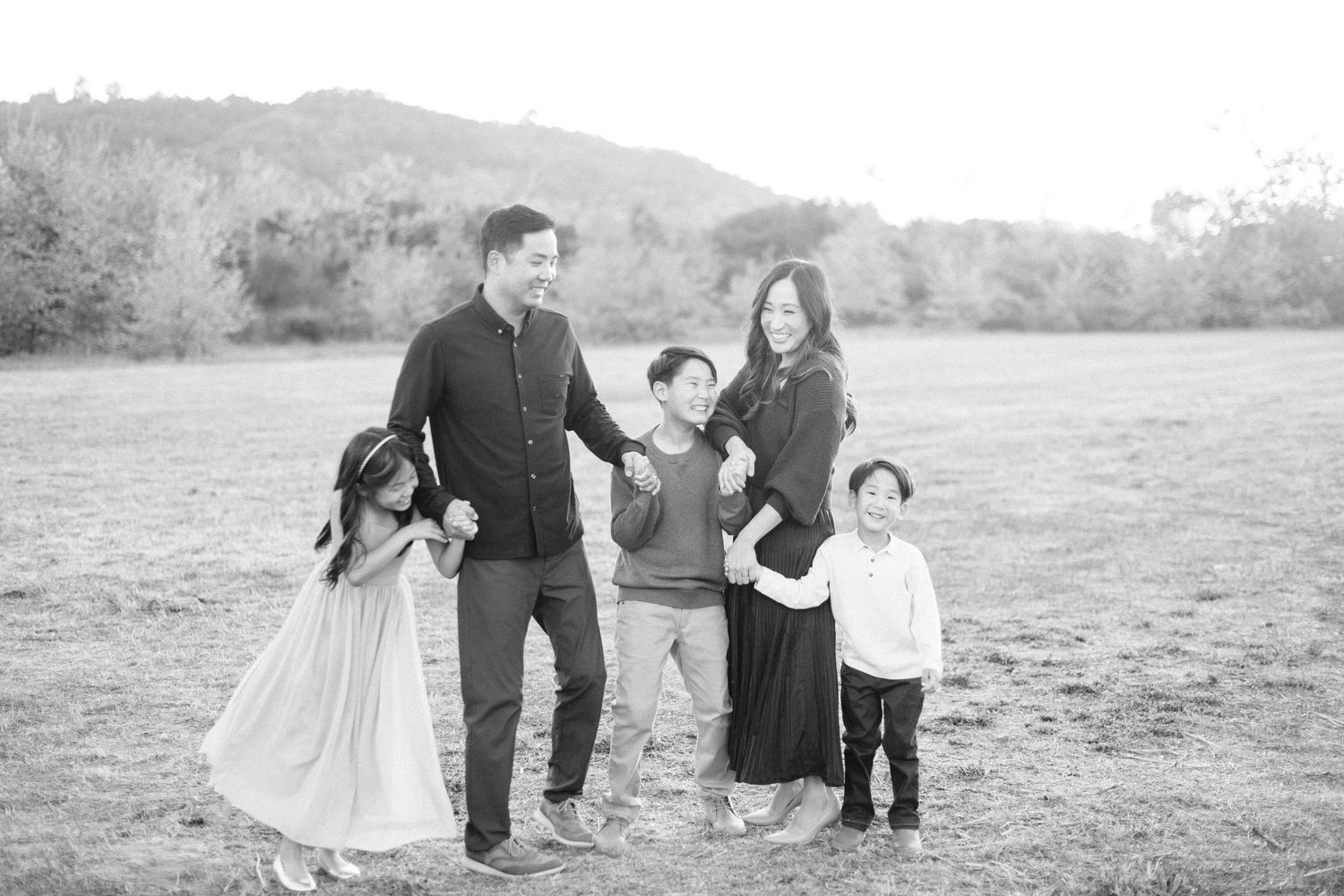 A happy family of five poses together in a black and white outdoor portrait.