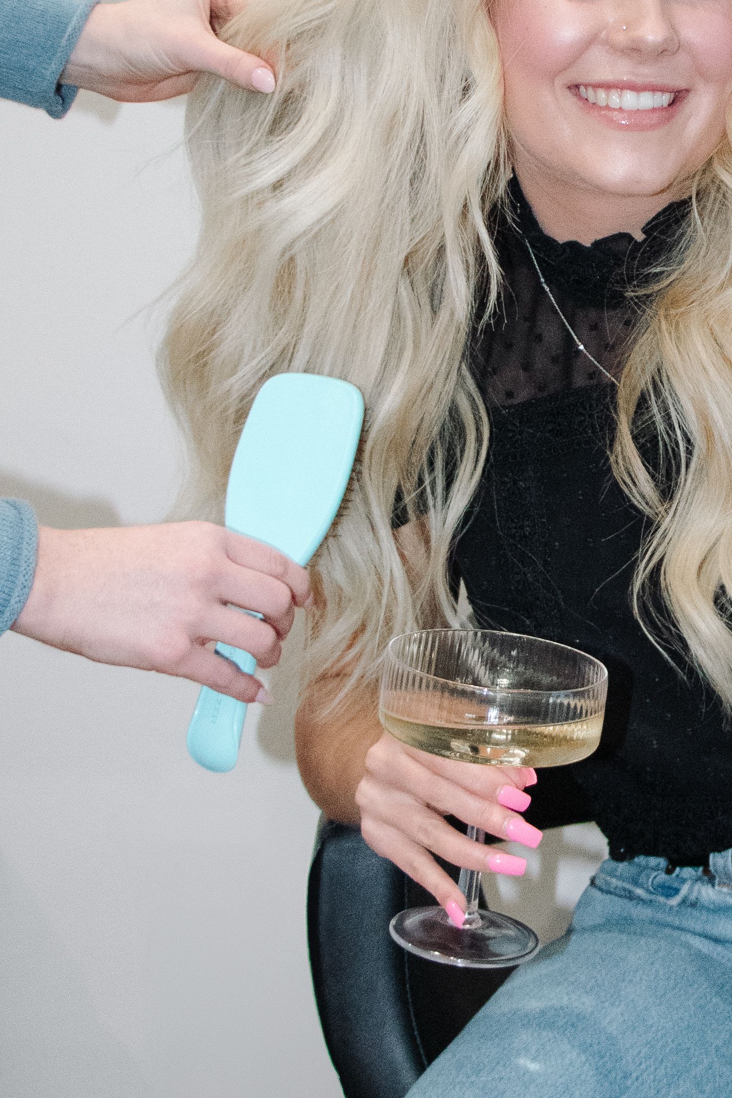 Close-up of blonde hair being brushed with a mint-colored hairbrush.